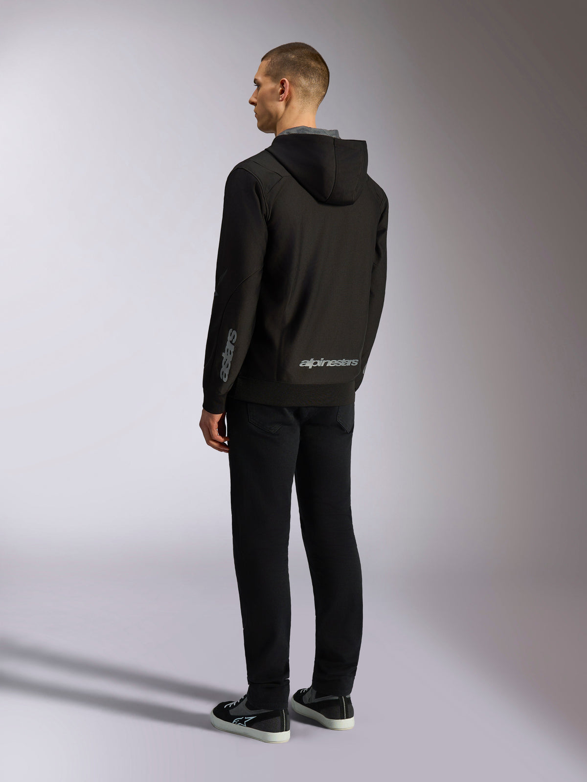 Alpinestars Sessions V3 Hoodie, streetwear casual de desporto motorizado, preto com logótipo cinzento na parte inferior das costas e no antebraço, fleece de poliéster com fecho frontal e capuz forrado a malha, vista traseira no modelo, design atlético moderno