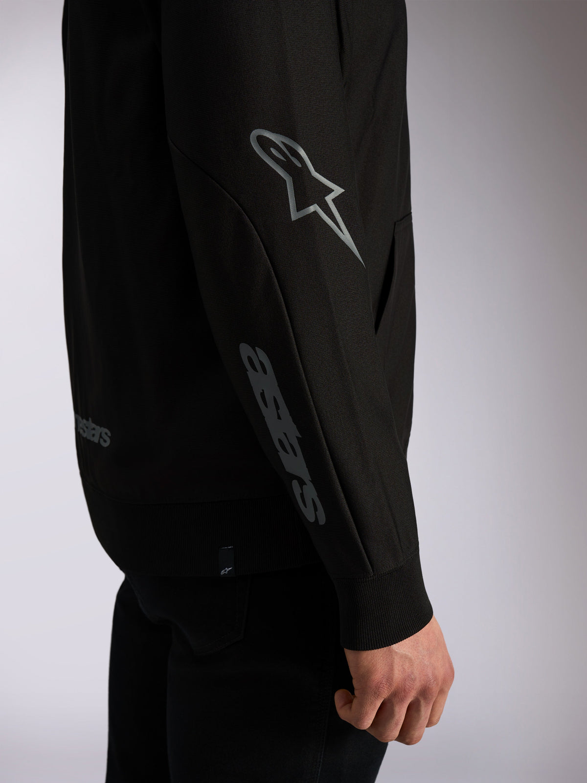 Alpinestars Sessions V3 Hoodie, streetwear casual preto, grande plano da manga com logótipo Astars cinzento no cotovelo e inscrição no antebraço, punhos canelados, design inspirado no desporto motorizado