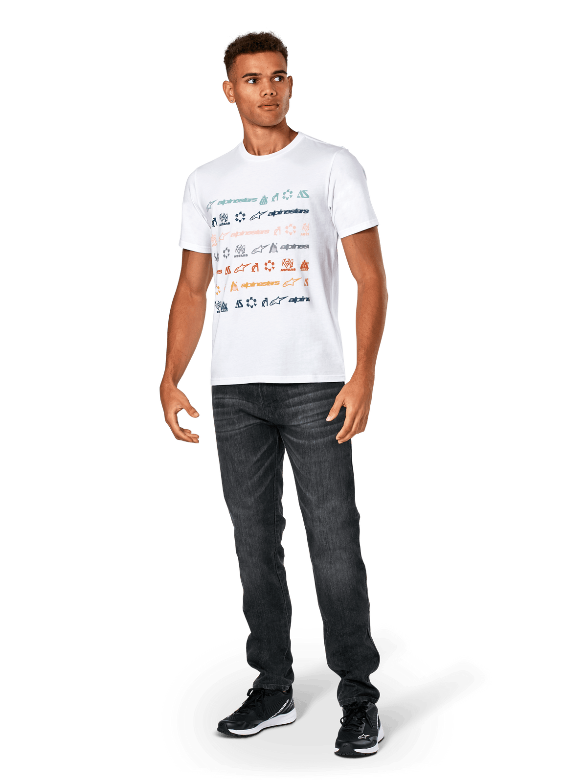 Alpinestars Glyfs CSF Tee, T-shirt de manga curta, branca, com grafismo listrado de vários logótipos na frente, usada com calças de ganga cinzento escuro e sapatilhas pretas, vestuário desportivo casual inspirado no desporto motorizado