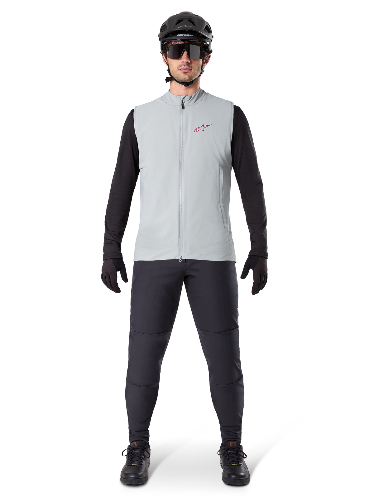 Alpinestars A-Dura Thermal Vest, cycling vest, Titanium Gray, worn with black long-sleeved jersey and black trousers, black helmet and sunglasses, featuring a red Alpinestars logo, lightweight thermal insulation for mountain biking