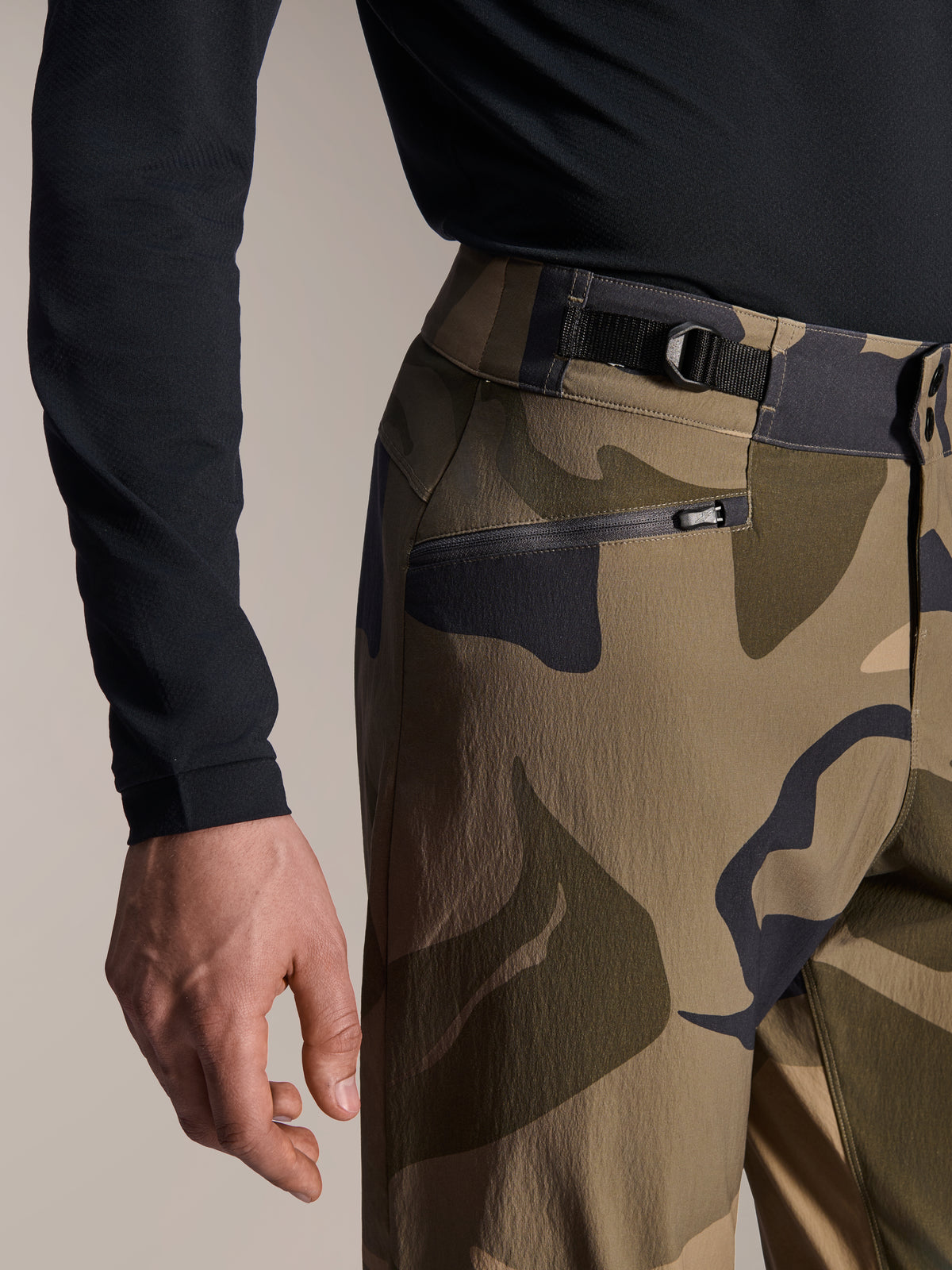 Alpinestars A-Dura Camo Pant, calças de MTB, camuflado castanho, vista de detalhe do ajustador lateral na cintura e do bolso com zíper e forro de malha, tecido elástico de 2 vias durável para mountain bike