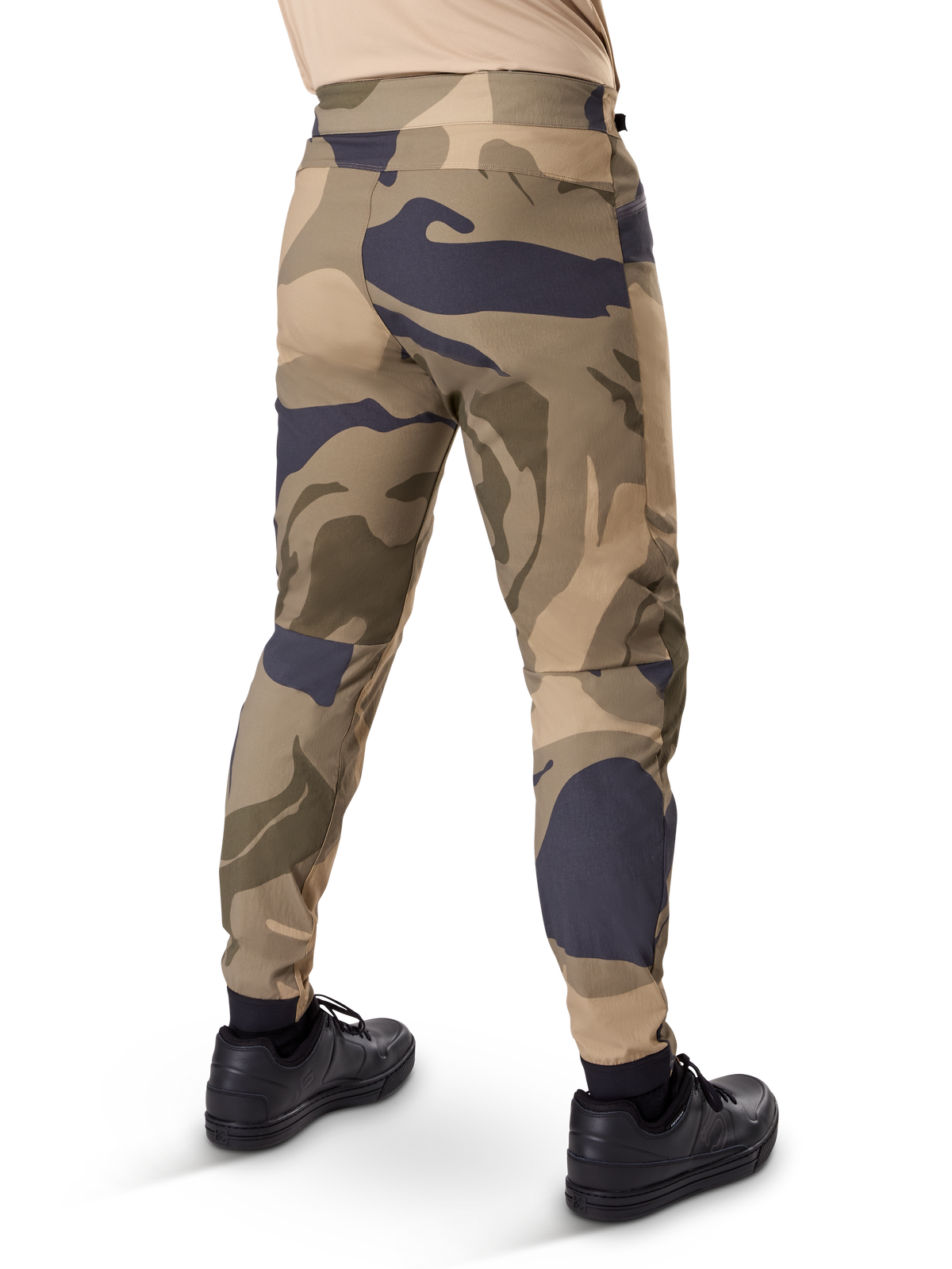 Alpinestars A-Dura Camo Pant, calças de MTB, padrão de camuflagem castanho com detalhes em bege e cinzento escuro, vista traseira com sapatilhas pretas, pernas afuniladas e punhos elásticos, tecido elástico de 2 vias durável para mountain bike