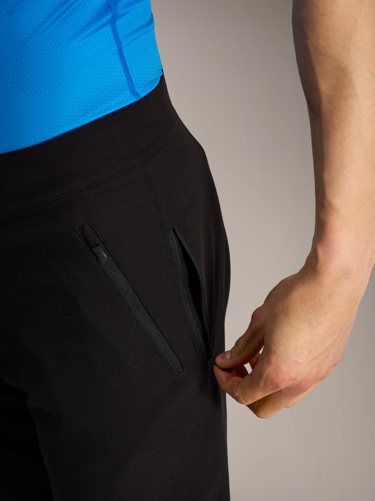 Calções pretos Alpinestars A-Dura Ride MTB, pormenor de mão a abrir um bolso lateral com fecho de correr seguro.