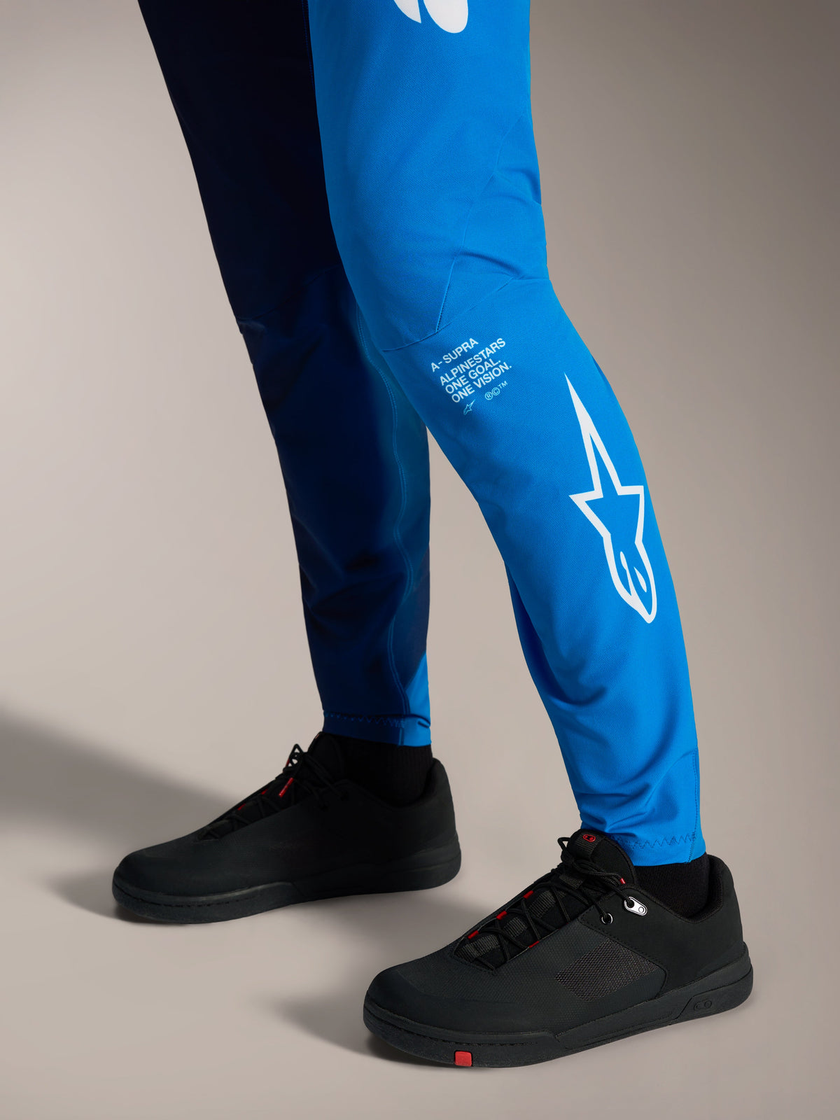 Calças A-Supra Elite Faded Bright Blue com logótipo Astars branco na perna e sapatos de BTT pretos.