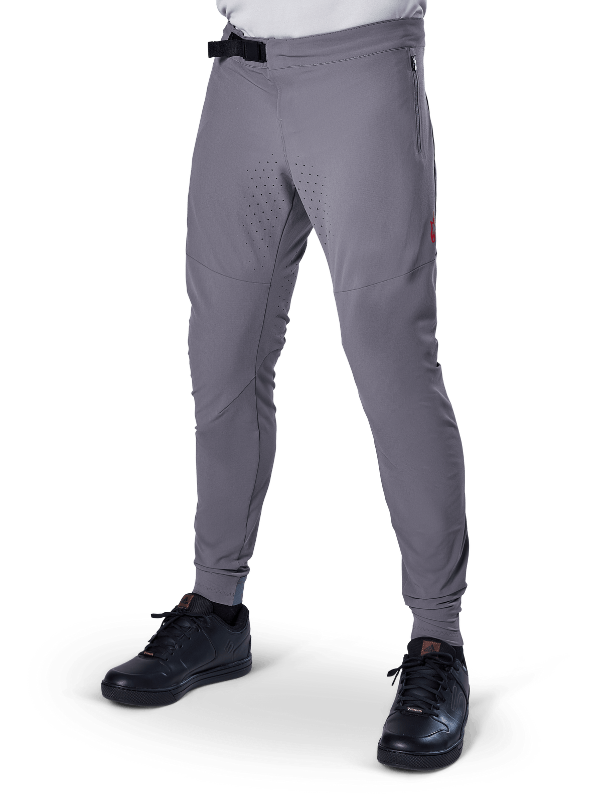Alpinestars A-Aria Elite Pants, calças de BTT cinzento escuro, painéis perfurados a laser nas coxas, fecho de fivela magnética preta, bolso com fecho, detalhe do logótipo vermelho, ajuste de performance justo, usadas com sapatilhas pretas