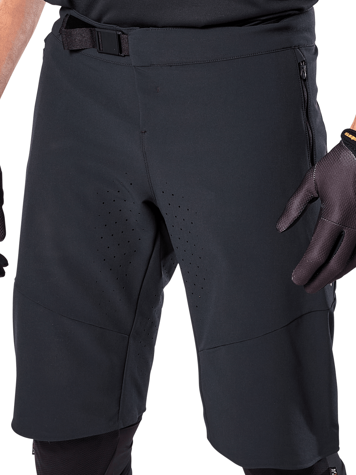 Calções Alpinestars A-Aria Elite em preto, vista detalhada da zona da cintura e das coxas, com fecho de fivela magnética, bolsos com fecho de correr e perfurações de ventilação cortadas a laser, usados com luvas de ciclismo pretas para BTT.
