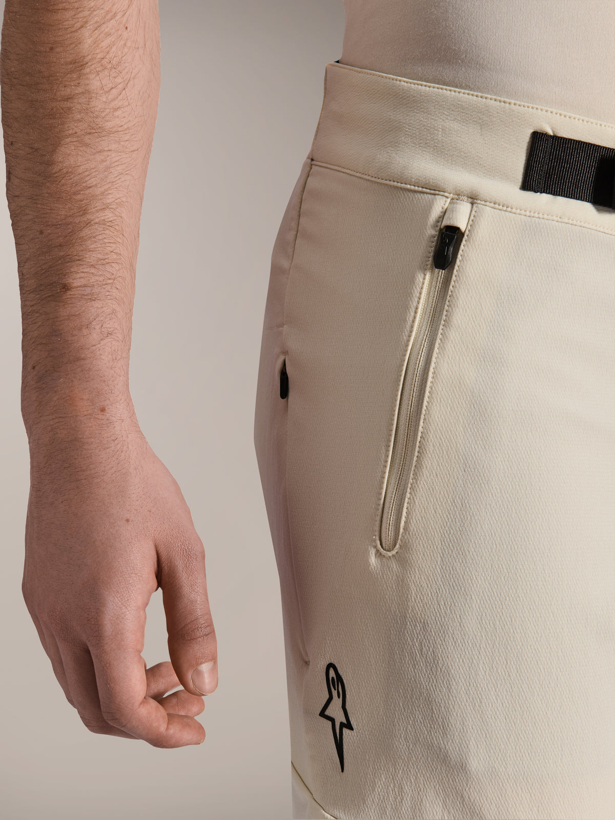 Alpinestars A-Aria Elite Shorts, calções de BTT, Ecru, vista lateral aproximada mostrando o bolso com fecho e o fecho de fivela magnética, vestuário de ciclismo de alta performance com detalhes pretos