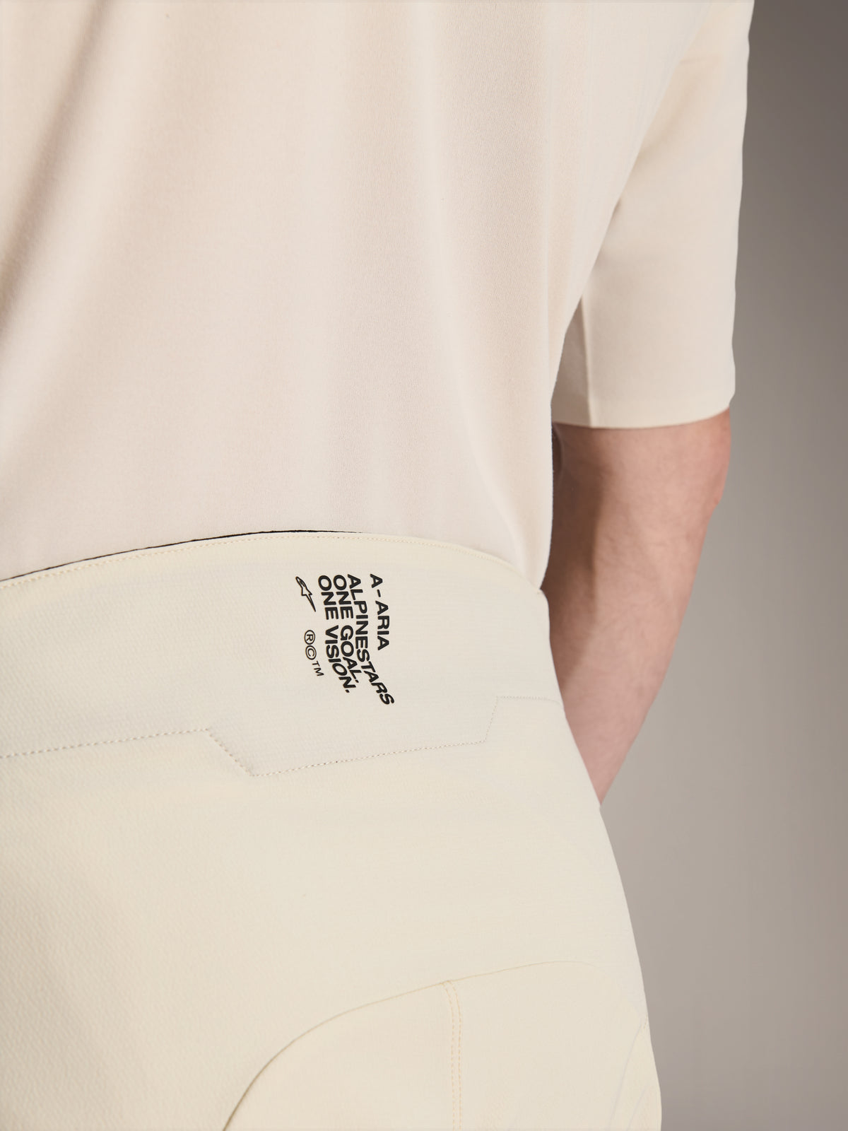 Alpinestars A-Aria Elite Shorts, calções de BTT, cor cru, grande plano da parte de trás do cós com o logótipo preto 'A-ARIA ALPINESTARS ONE GOAL. ONE VISION.', vestuário de ciclismo de alta performance