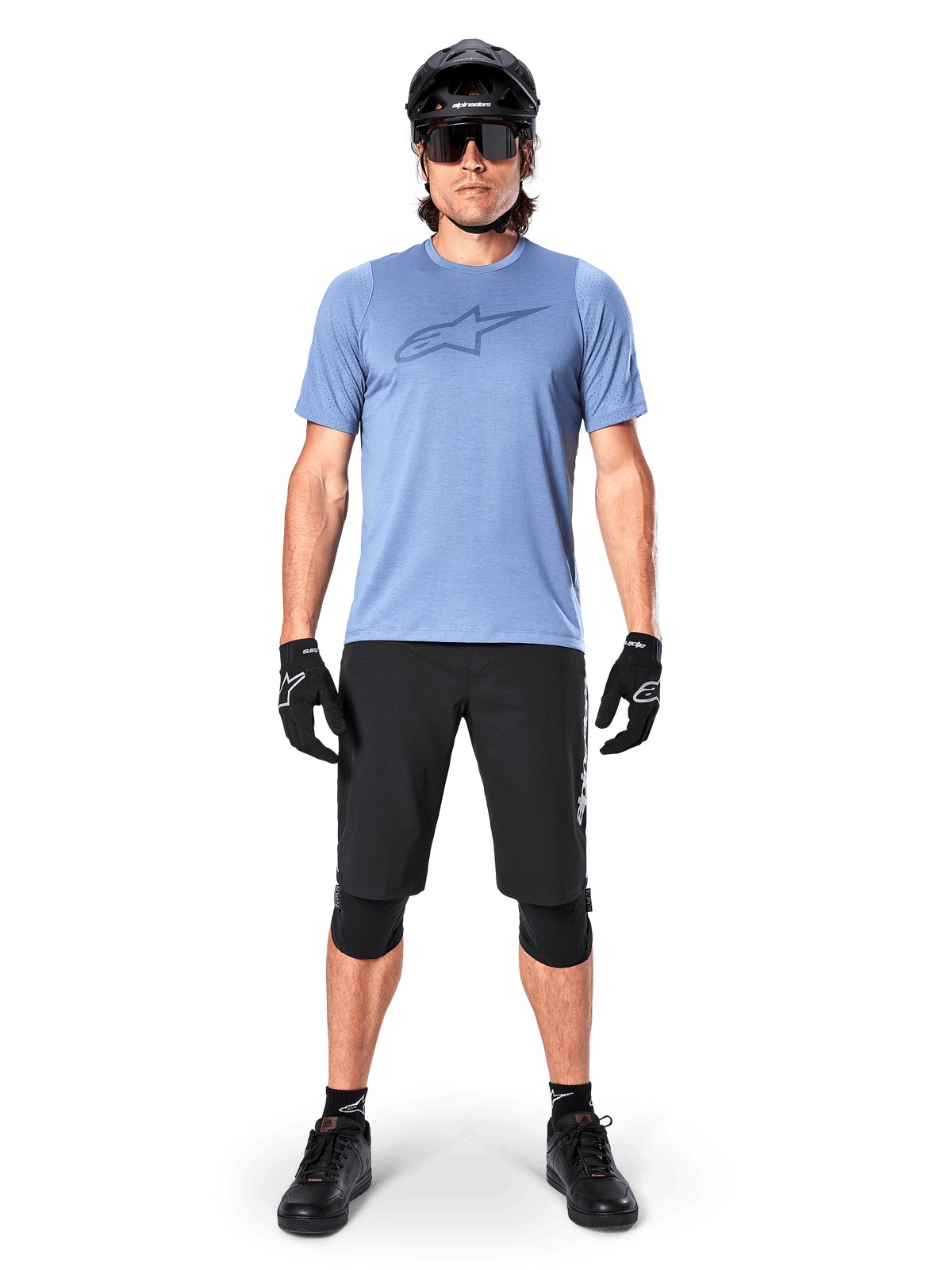Calções Alpinestars A-Dura Elite, calções pretos de mountain bike, usados com uma t-shirt azul-claro, capacete preto, óculos de sol e joelheiras, vestuário profissional de ciclismo fora de estrada