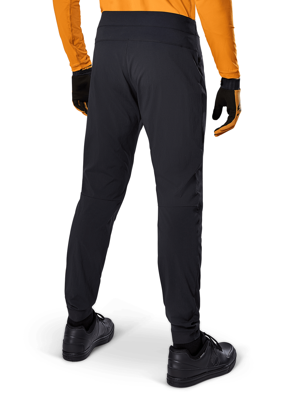 Alpinestars A-Dura Pants, Black MTB Pants, rear view, worn with an orange long-sleeve jersey and black gloves, featuring elasticated cuffs and durable textile material for mountain biking.