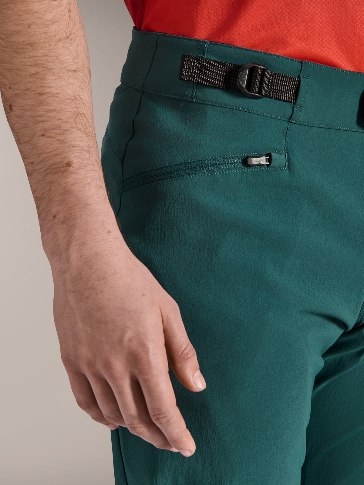 Pormenor das calças Alpinestars A-Dura em verde Dark Pine, apresentando o fecho lateral ajustável e um bolso com fecho e forro de malha, vestuário de mountain bike durável para a prática de trilhos fora de estrada.
