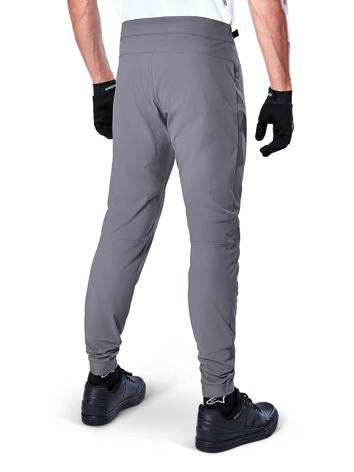 Calças Alpinestars A-Dura, calças de MTB, cinza escuro, vista traseira do modelo a usar o equipamento, com tecido durável com elasticidade em 2 direções e punhos elásticos, coordenadas com luvas e sapatilhas pretas para um visual pronto para o ciclismo