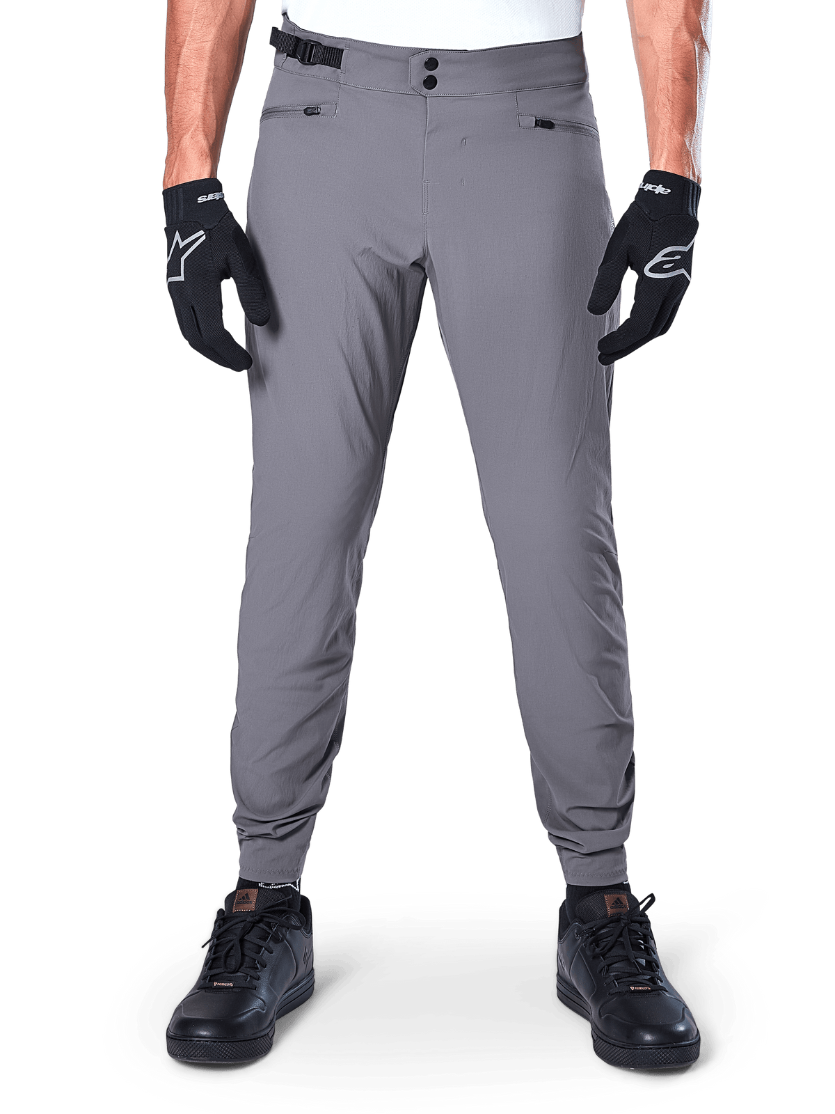 Calças Alpinestars A-Dura, calças de BTT cinzento-escuro, vista frontal, usadas com luvas pretas e ténis pretos, com fecho de cintura de pressão duplo, bolsos com fecho de correr e punhos elásticos, vestuário de ciclismo durável para trail
