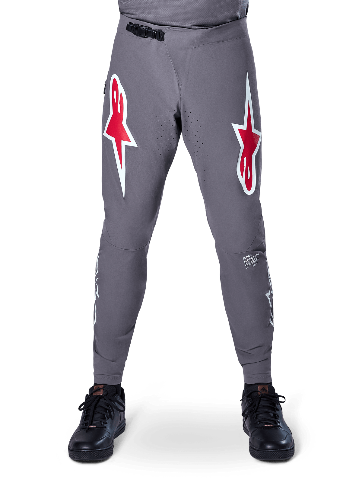 Calças Alpinestars A-Supra Race, calças de BTT, cinzento escuro, com grandes logótipos de estrela em vermelho e branco nas coxas, ventilação perfurada a laser na zona interna das pernas e fecho de cintura por catraca preto, concebidas para corridas de BTT.