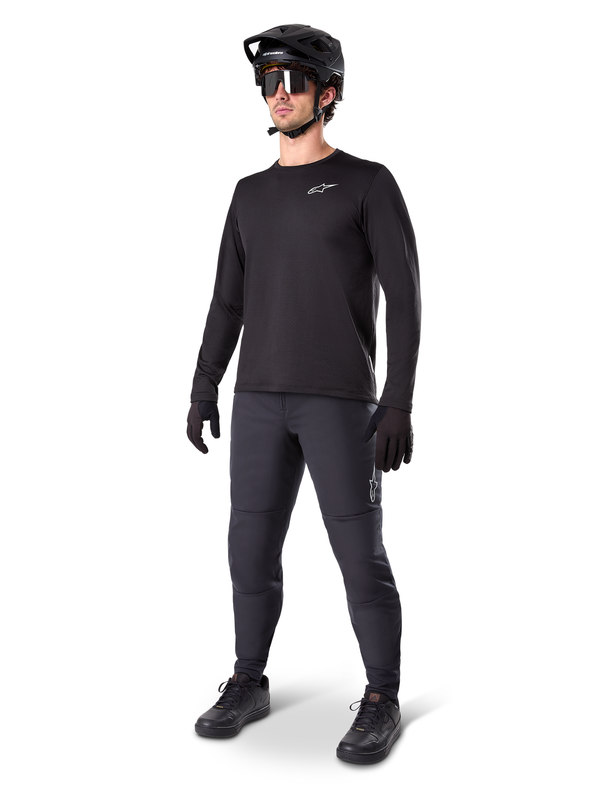 Model wearing Alpinestars A-Dura Thermal Jersey, Black long-sleeve MTB jersey, black mountain bike helmet, sunglasses, and dark grey pants, featuring a small white logo on the chest, insulated fleece construction for cold-weather riding