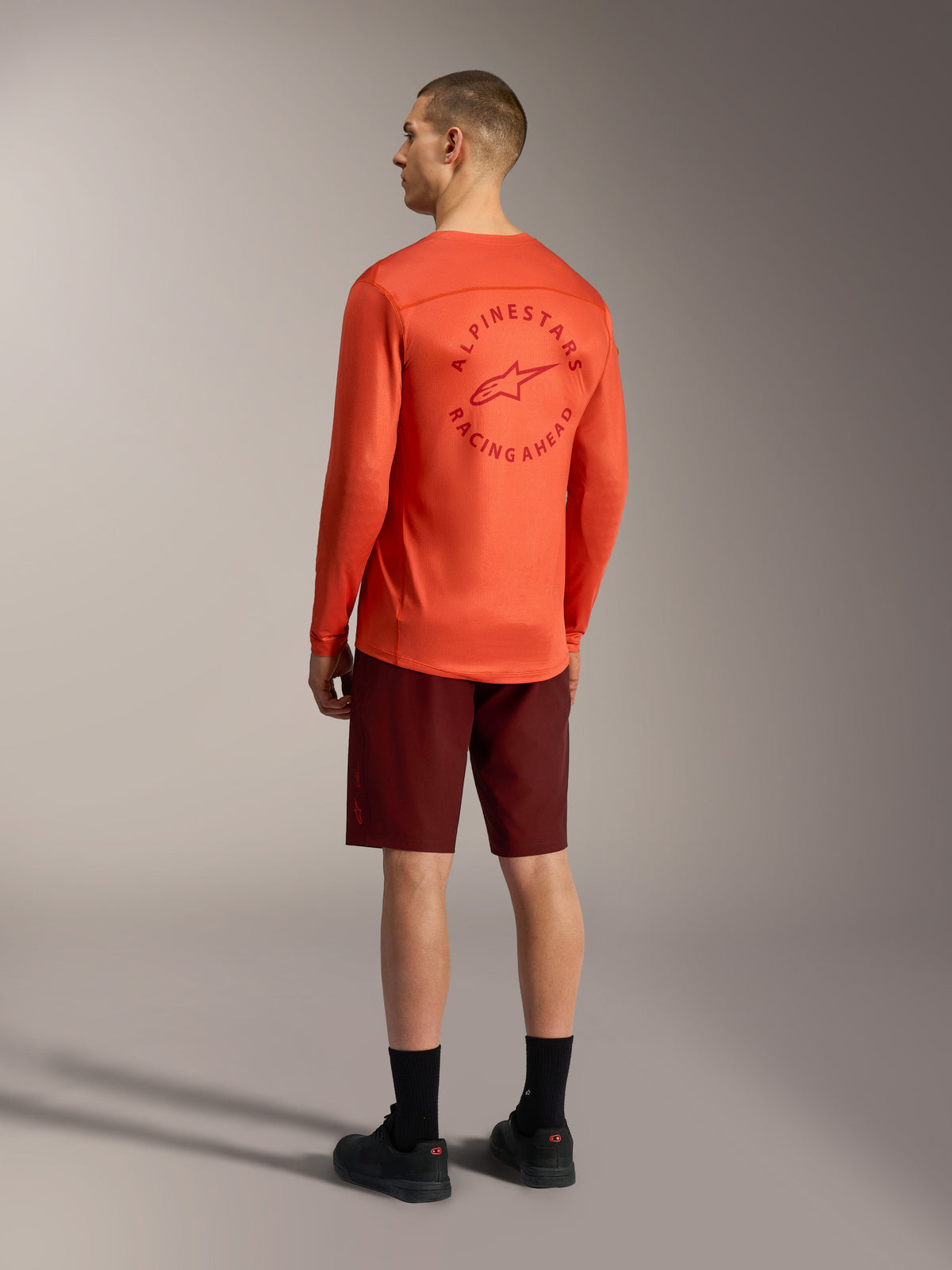 Alpinestars A-Dura Ride Shorts in Bordeaux and bright orange A-Dura Air LS Jersey, rear view of mountain bike gear.