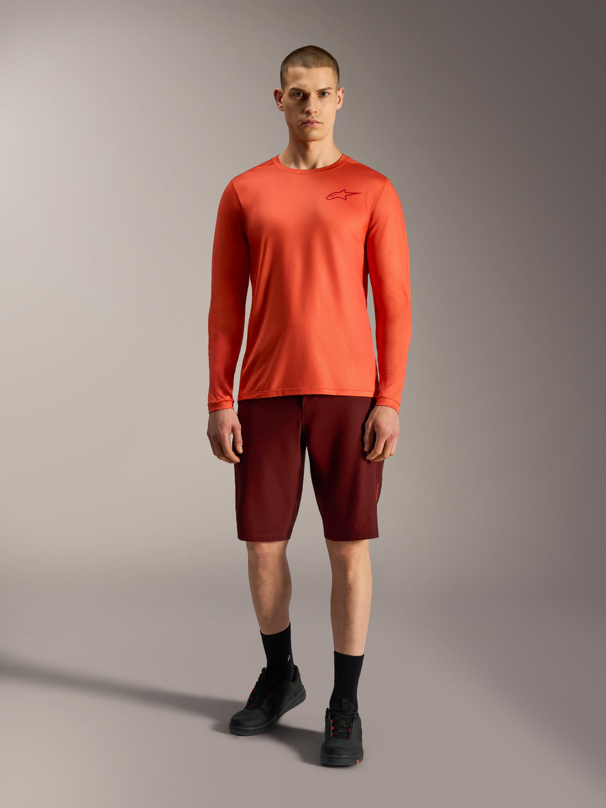 Calções Alpinestars A-Dura Ride 2026 em bordeaux e camisola laranja de manga comprida, vestuário de BTT para homem.