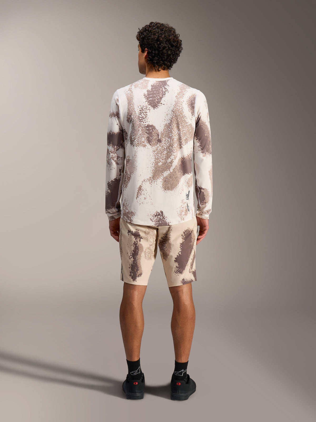 Camisola A-Dura Ride de manga comprida em Sand Camo, vista traseira com poliéster reciclado e calções de BTT a condizer.