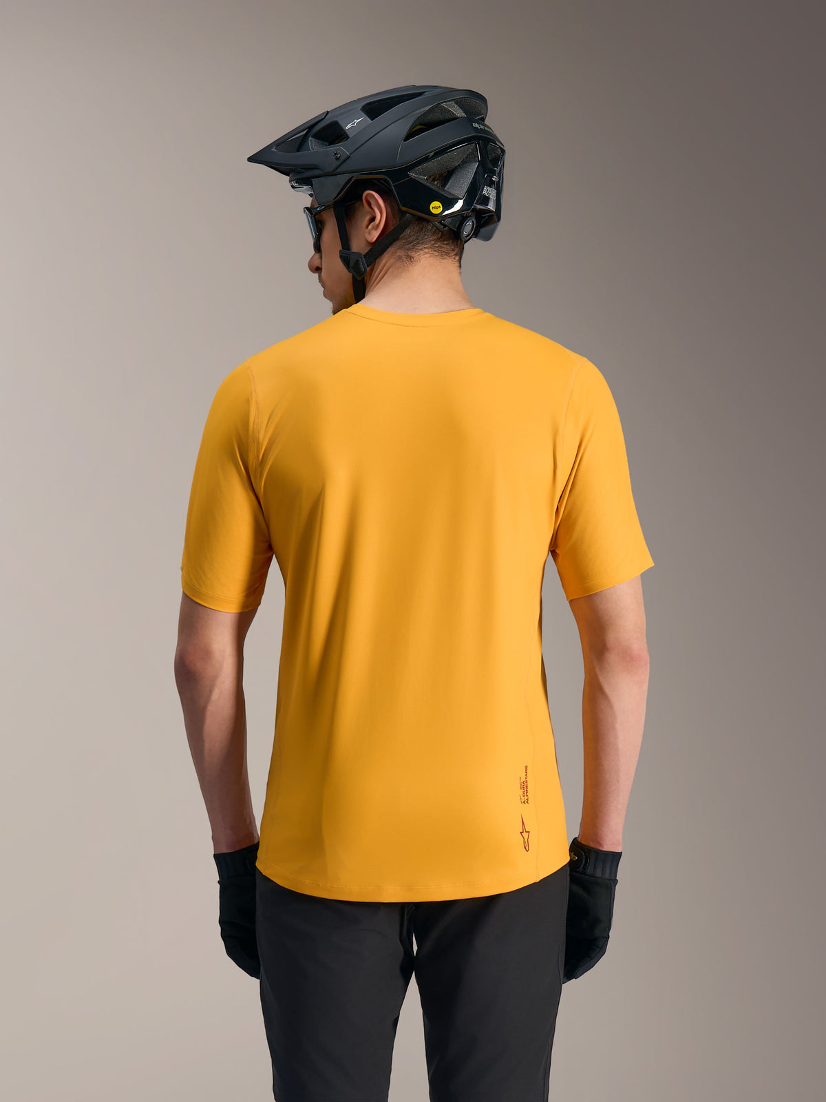 Camisola Alpinestars A-Dura Ride laranja, topo de MTB leve visto de trás com capacete, logótipo e design de cauda mais longa