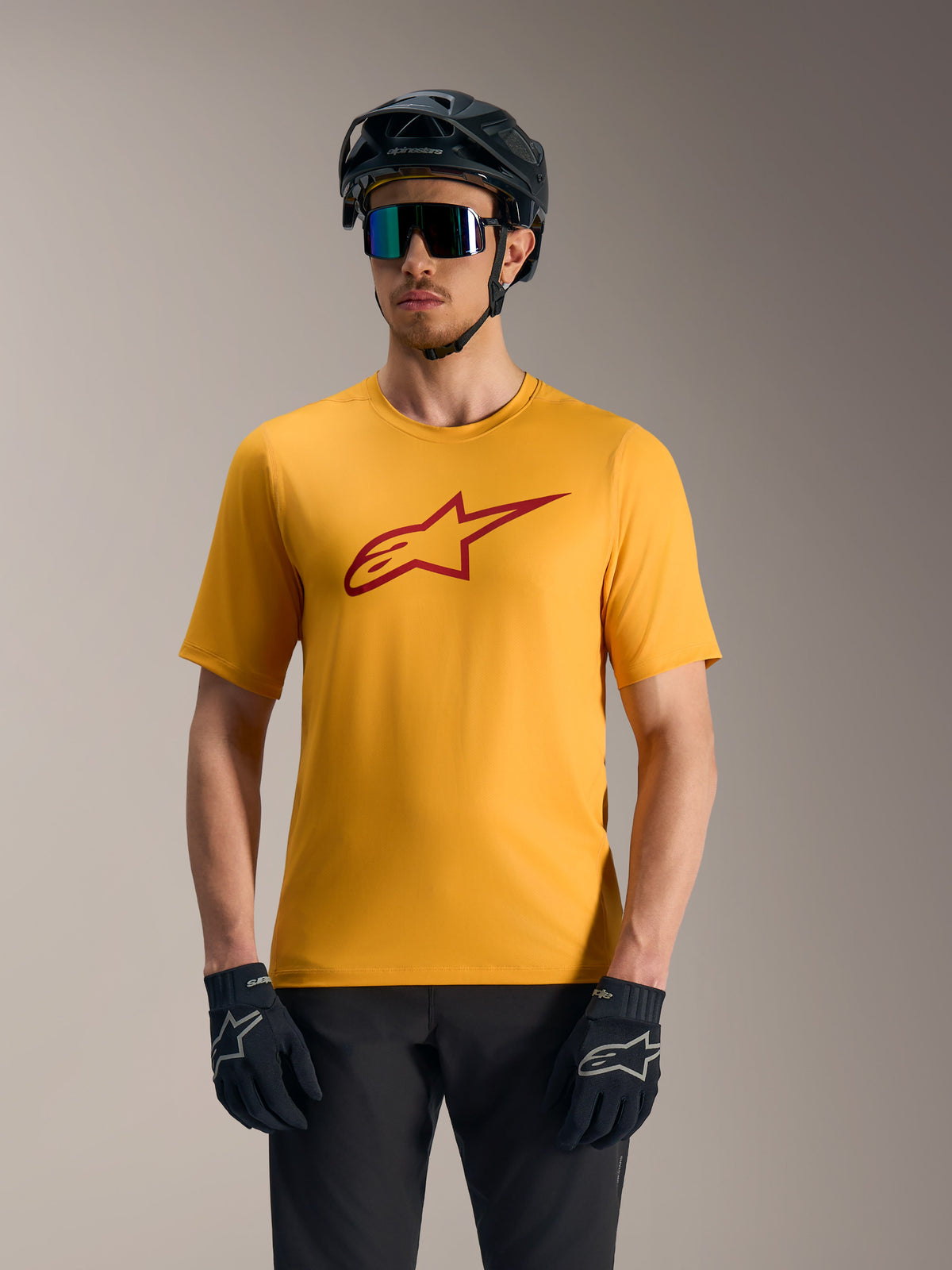 Camisola Alpinestars A-Dura Ride laranja de mangas curtas, com logótipo Astars vermelho, capacete e luvas de BTT.