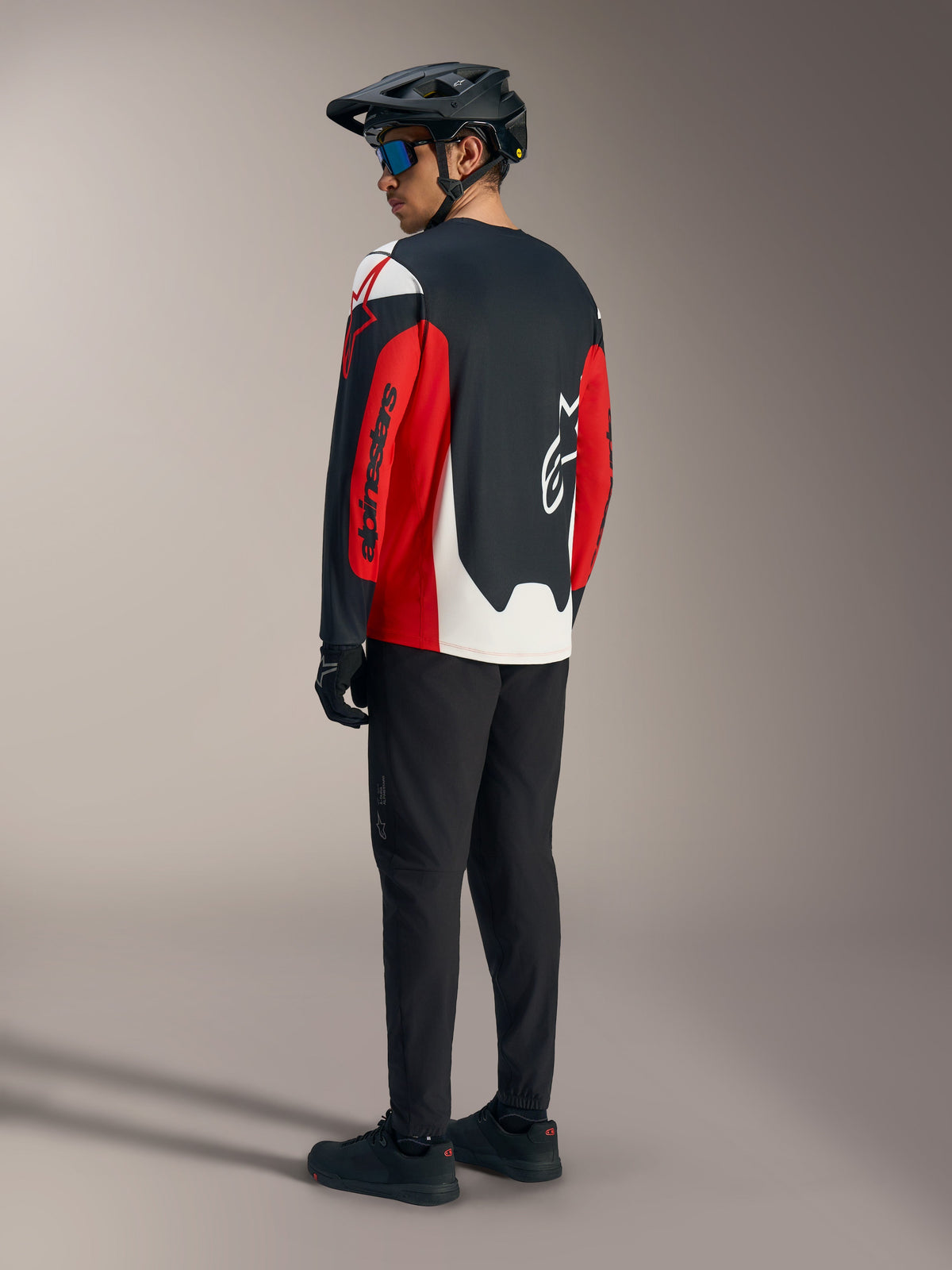 Red A-Dura Race Long Sleeve Jersey featuring bold Alpinestars graphics, shown from the back in a mountain bike kit.