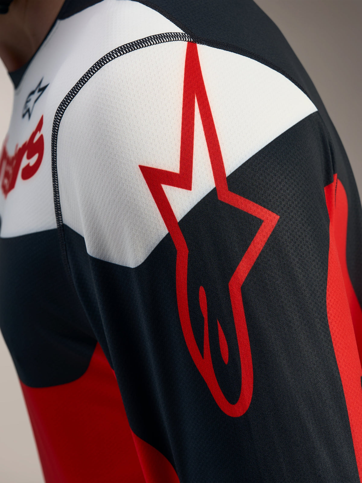 Red and black A-Dura Race Long Sleeve Jersey detail with an Alpinestars star logo on breathable jacquard mesh fabric.
