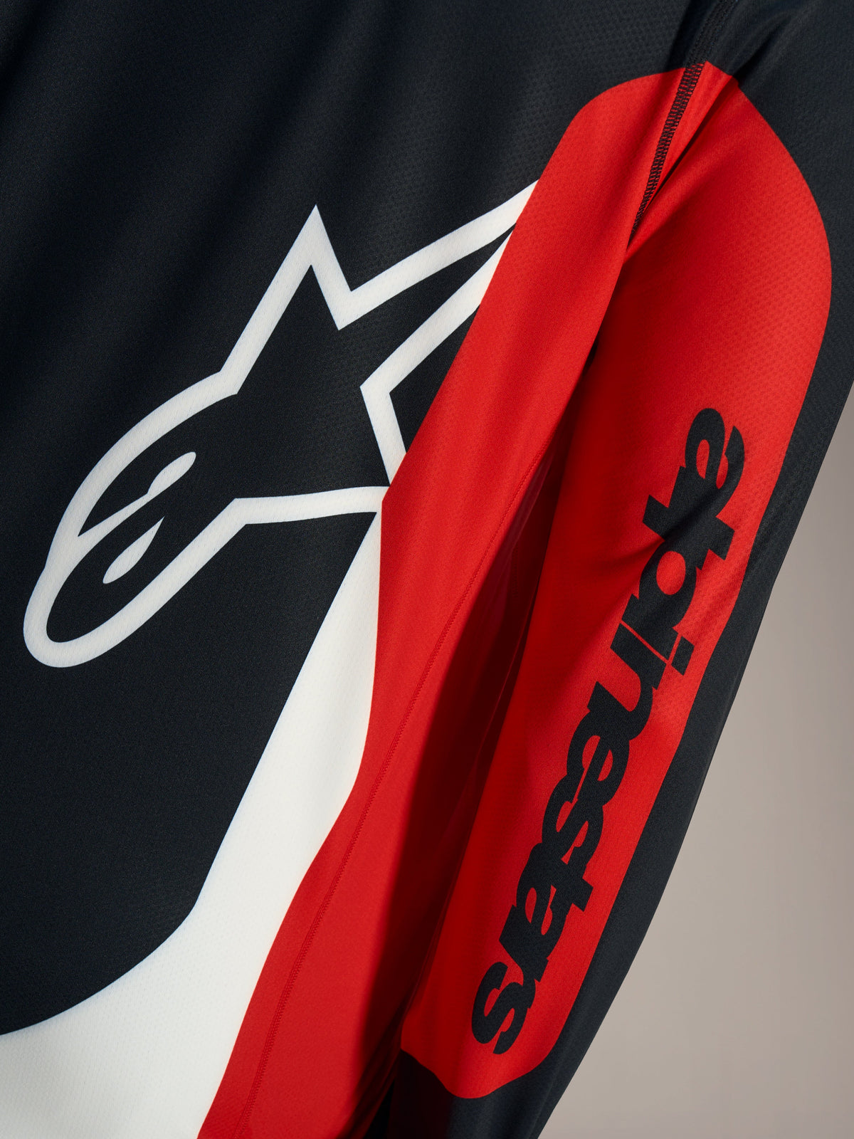 A-Dura Race Jersey detail featuring white Astars logo and black wordmark on red and black technical mesh fabric.