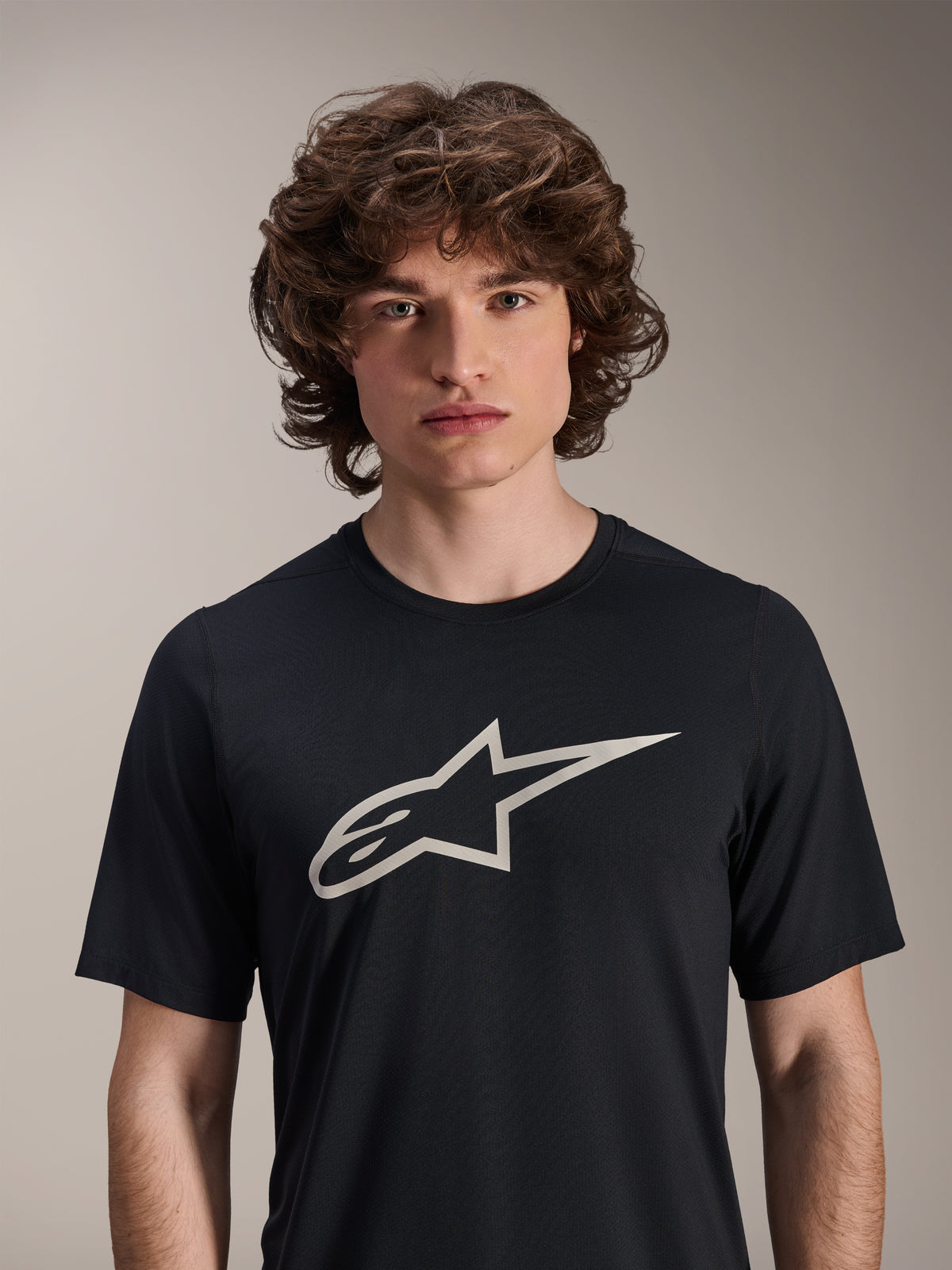 Alpinestars A-Dura Astar Short Sleeve Jersey, preta, com um grande logótipo Astar branco no peito, vestida por um modelo masculino, vestuário de performance casual para BTT