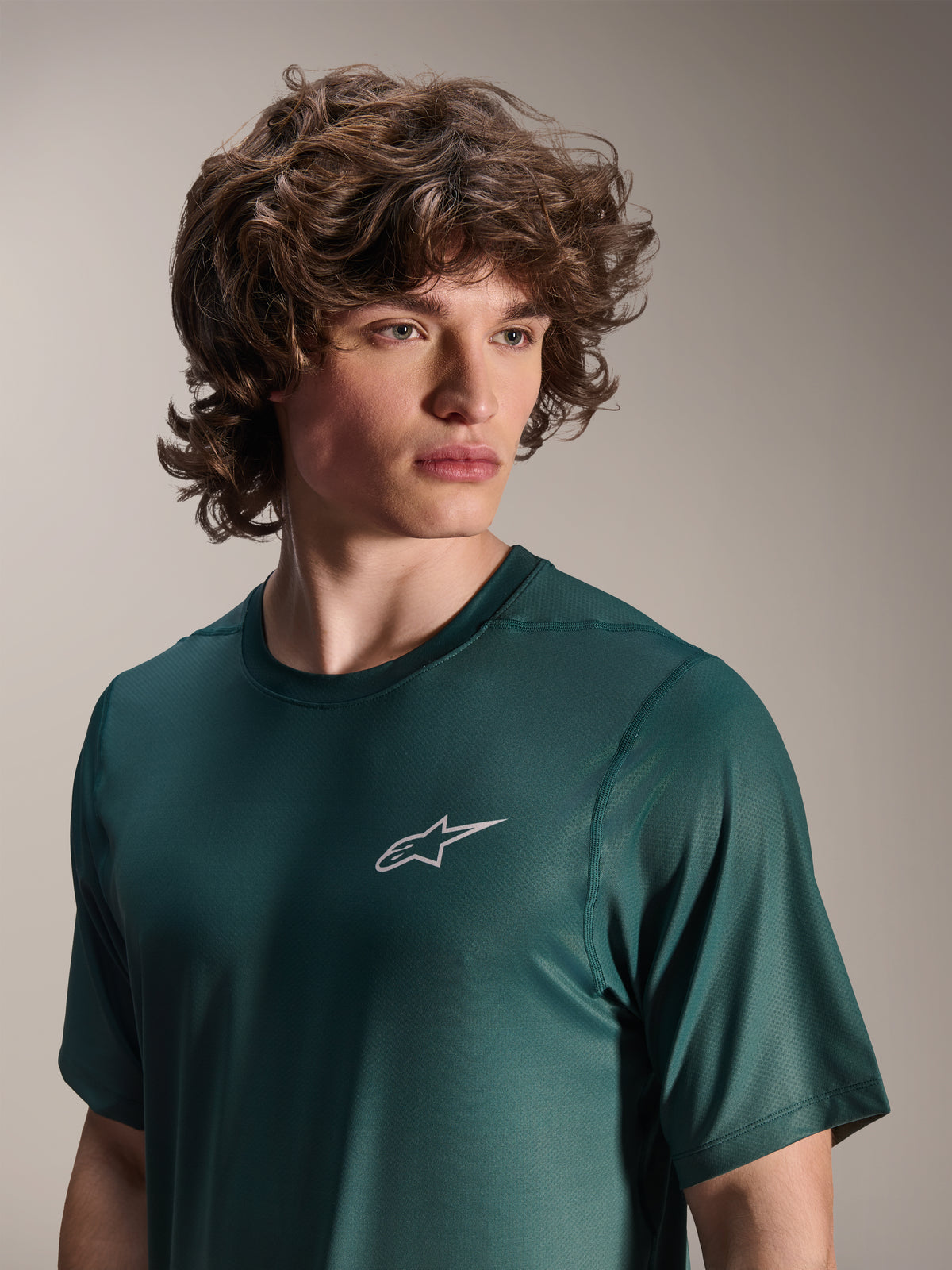 Camisola de Manga Curta Alpinestars A-Dura Rise, verde Silver Pine, vestida por um modelo, pequeno logótipo Astars branco no peito, tecido jacquard de alta performance, vestuário casual de bicicleta de montanha