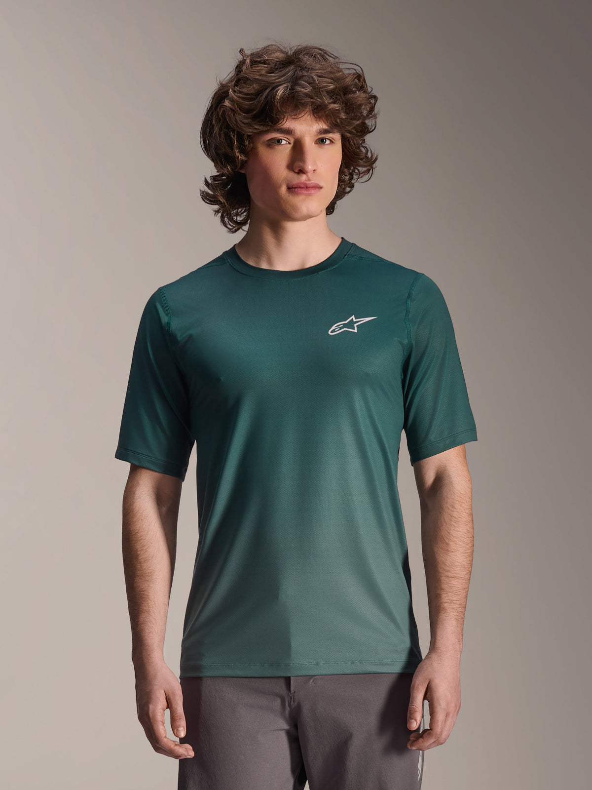 Alpinestars A-Dura Rise Jersey - Manga Curta, verde escuro Silver Pine, vestida por um modelo, com logótipo Astars branco no peito, tecido jacquard leve com absorção de humidade, camisola de performance casual para ciclismo de montanha