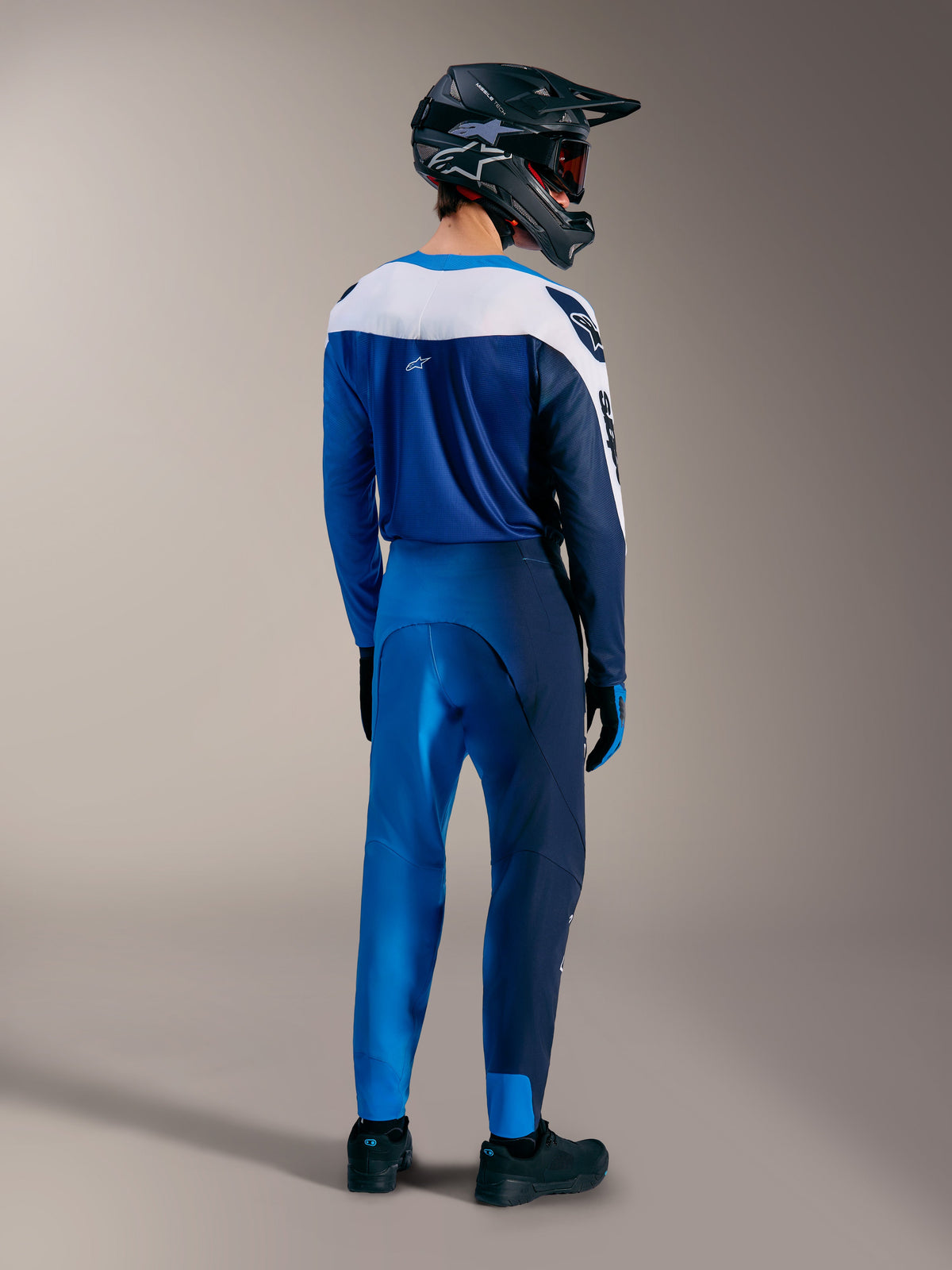 Equipamento Alpinestars A-Supra Elite MTB em azul degradé, com camisola e calças vistas de costas e capacete integral.