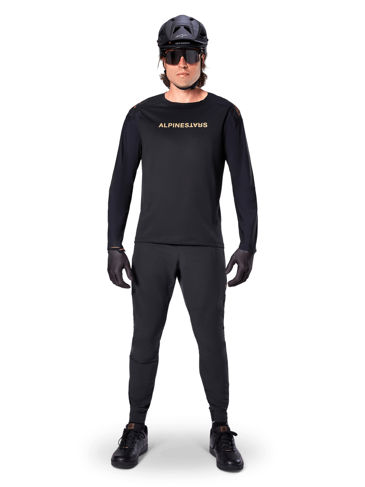 Alpinestars A-Aria Polartec Switch Long Sleeve Jersey, preto, usado por um ciclista com calças técnicas pretas a condizer, capacete preto, óculos de sol e luvas pretas, equipamento de performance de BTT para trilhos fora de estrada