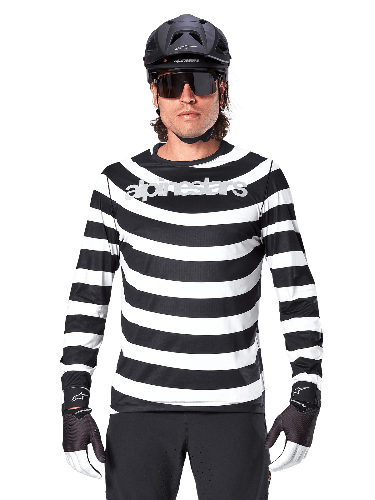 Ciclista masculino com Jersey de Manga Comprida Alpinestars A-Aria Oscar, listas horizontais pretas e brancas, logótipo Alpinestars refletor no peito, combinado com capacete de MTB preto, óculos de sol de ciclismo e luvas de performance