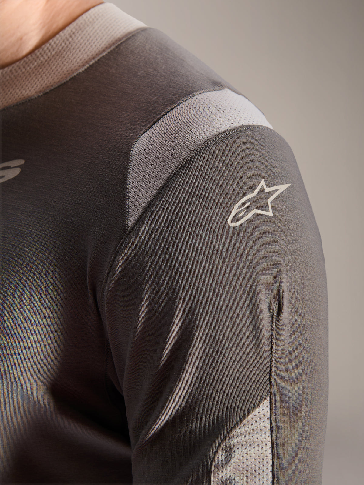 Alpinestars A-Dura Dri Wool Jersey - Manga Comprida, cinzento escuro, vista detalhada do ombro e da manga com painéis de ventilação em malha cinzento claro e o logótipo Astars branco no tecido técnico drirelease.