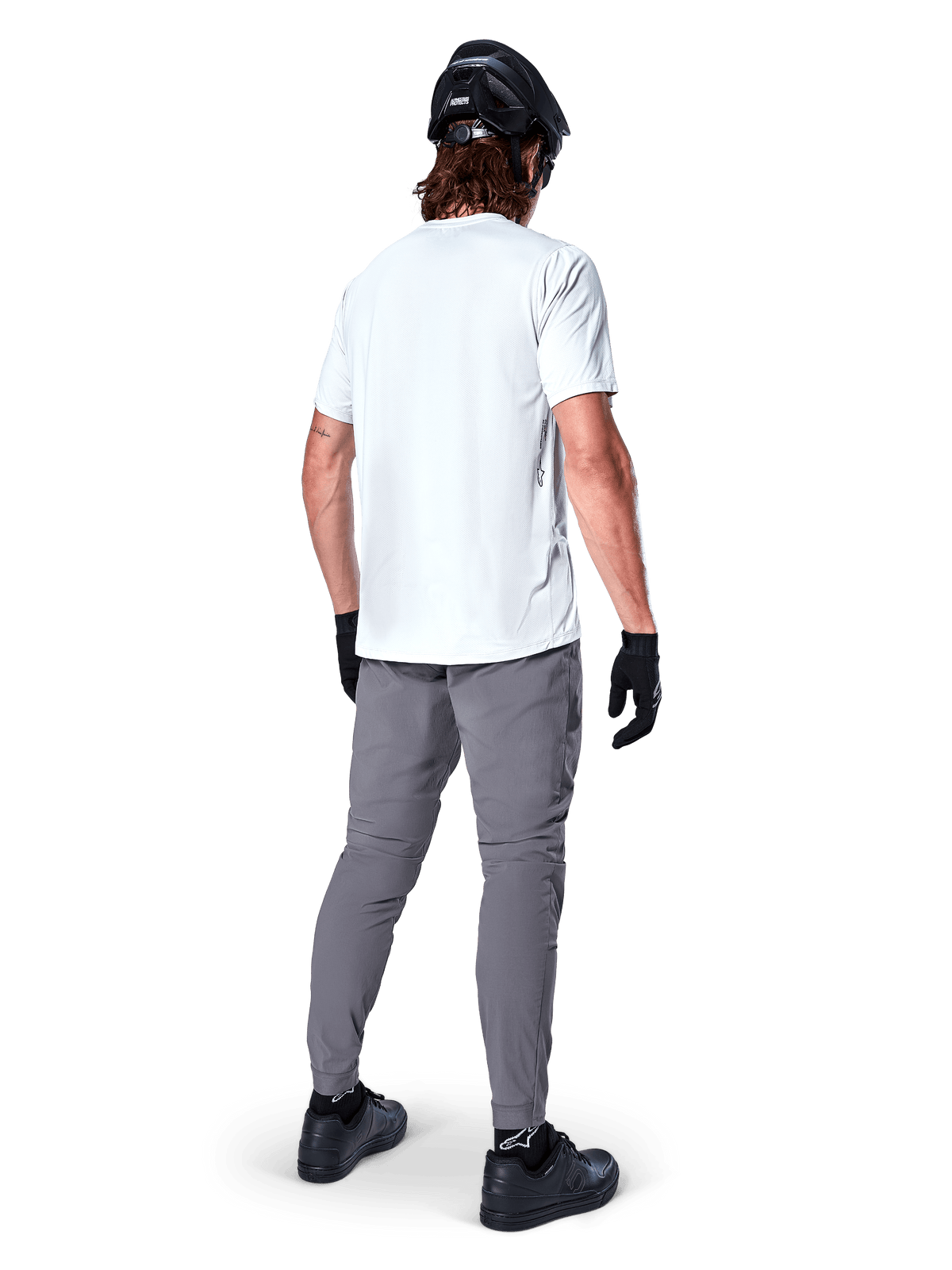 Alpinestars A-Dura Oscar Short Sleeve Jersey em White Dove, vista traseira usada por um ciclista com calças de ciclismo cinzentas, capacete e luvas pretos, vestuário técnico de BTT para trilhos fora de estrada