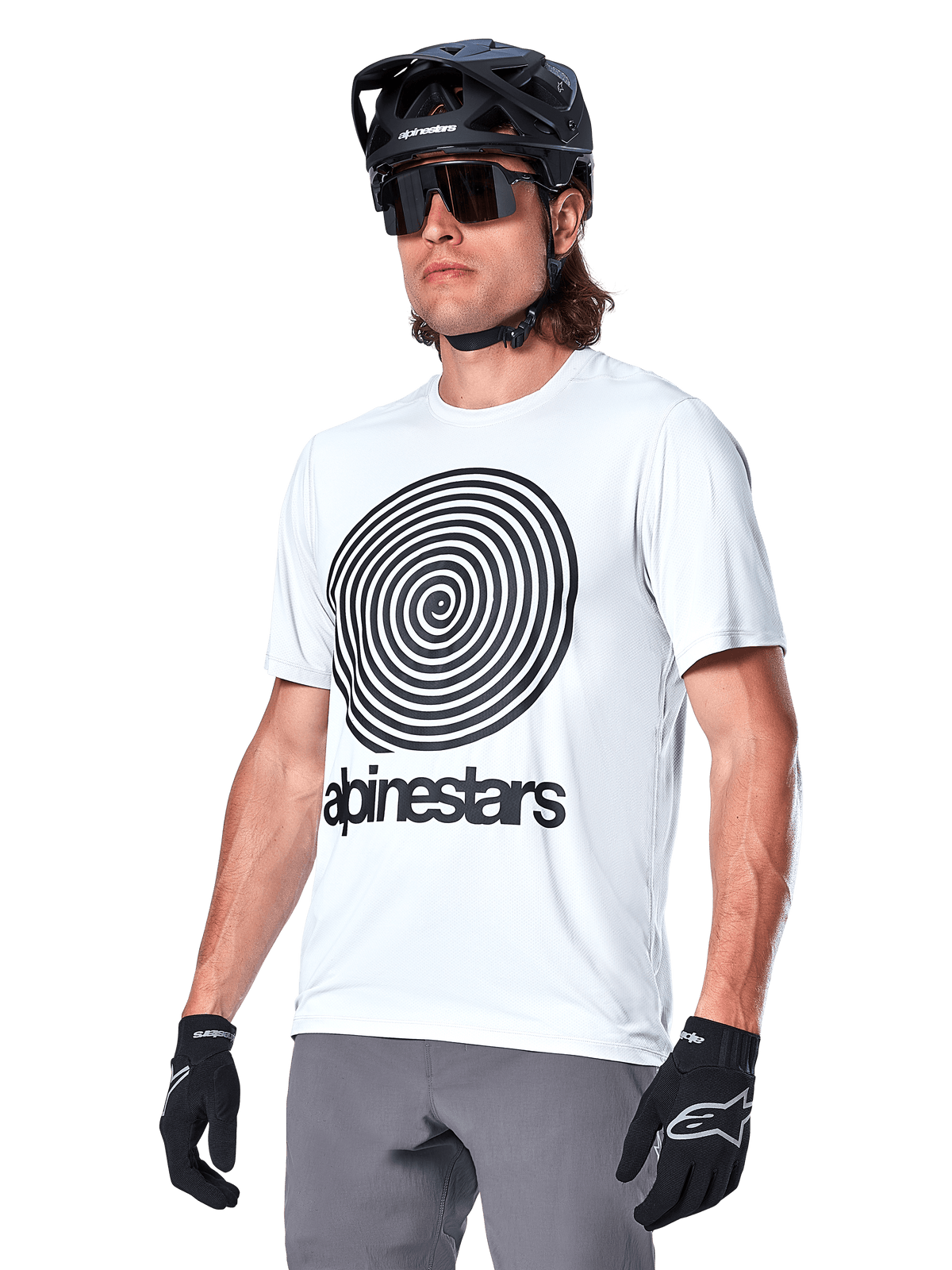 Alpinestars A-Dura Oscar Jersey - Manga Curta, cor White Dove com gráfico em espiral heritage e logótipo pretos, usada com capacete de BTT e luvas pretas, vestuário desportivo de performance para ciclismo de montanha