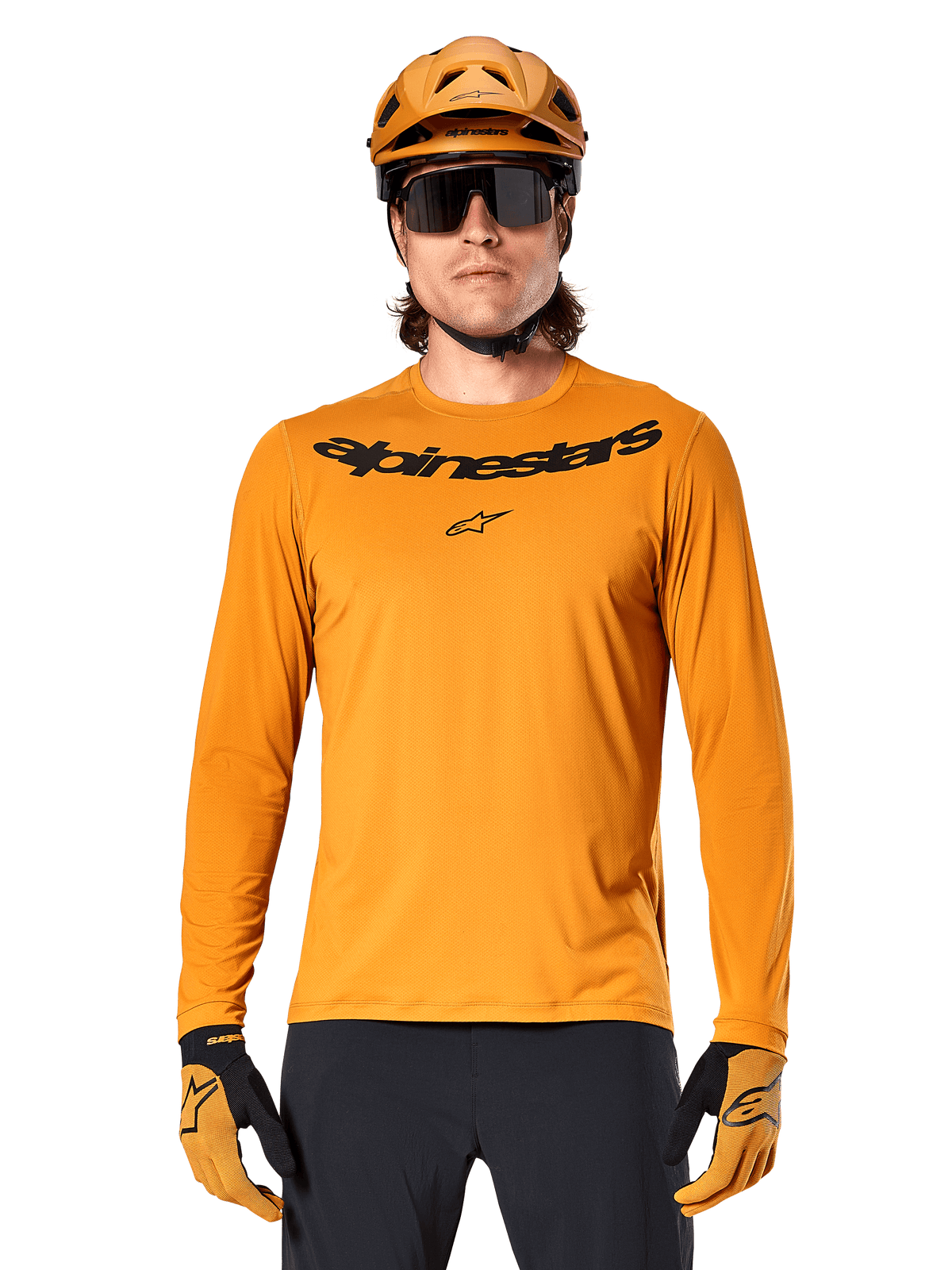 Alpinestars A-Dura Rocker Long Sleeve Jersey in Dark Gold, featuring a black wordmark logo on the chest, worn with a matching gold helmet and gloves for mountain bike performance.