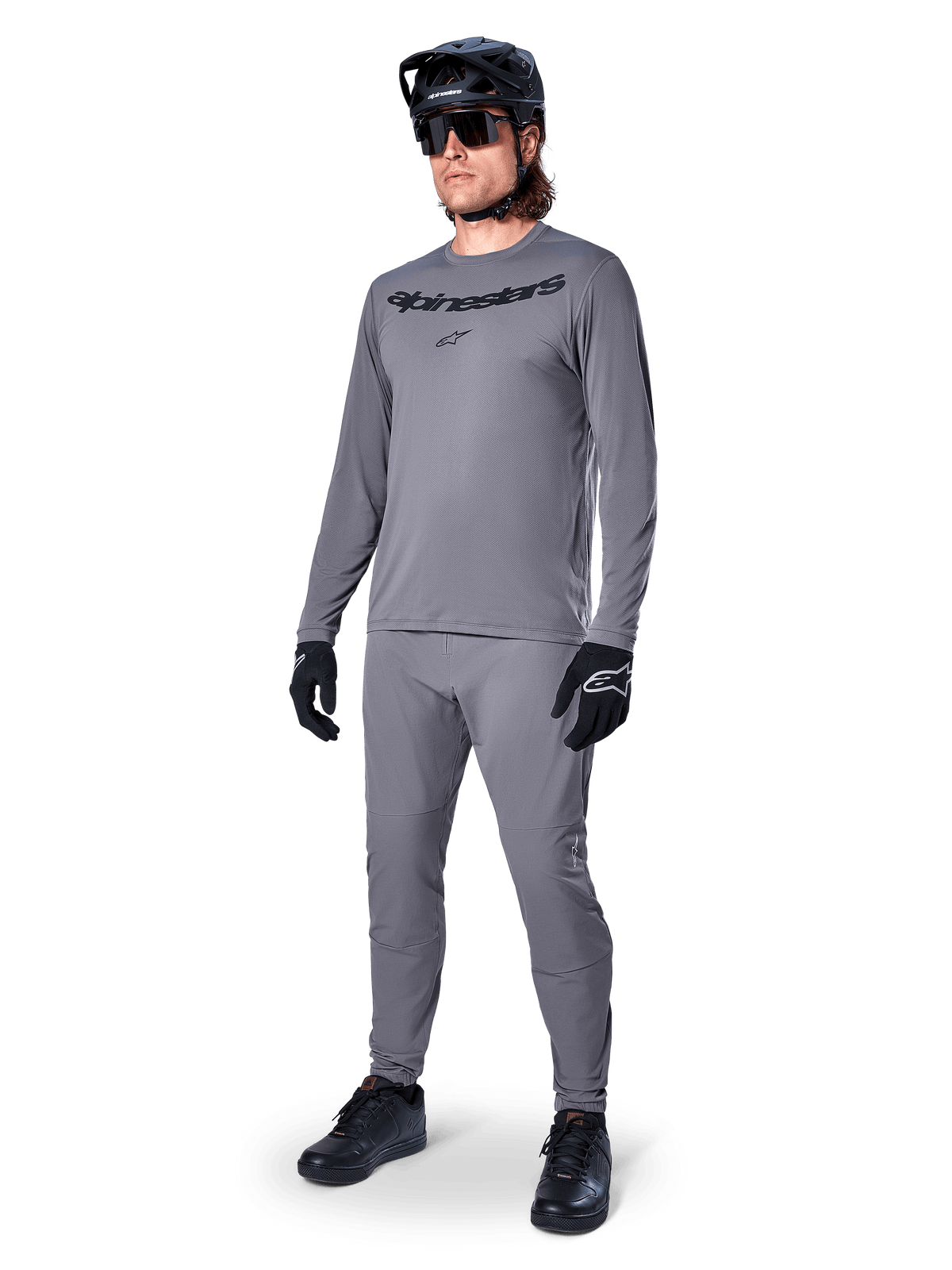 Camisola Alpinestars A-Dura Rocker - Manga Comprida, cinza escuro, vestida por um modelo com calças cinzentas a condizer, capacete de BTT preto, óculos de sol e luvas, estilo BTT casual para condução fora de estrada