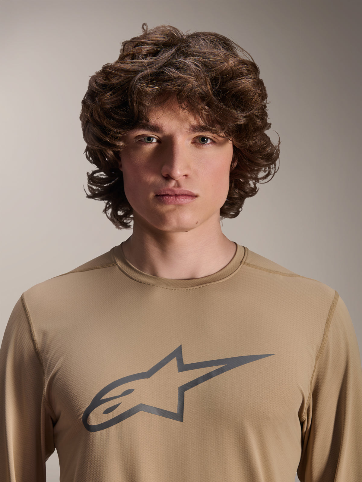 Camisola de manga comprida Alpinestars A-Dura Astar, castanho claro, usada por modelo masculino, com um logótipo Astars grande no peito, textura de tecido jacquard, vestuário casual de BTT