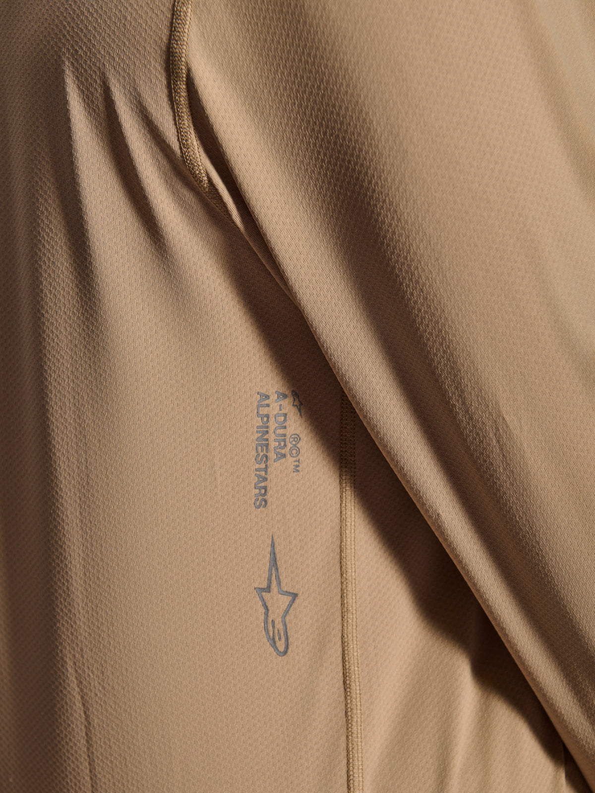 Alpinestars A-Dura Astar Long Sleeve Jersey, camisola de ciclismo BTT, castanha, grande plano que mostra a textura do tecido jacquard, logótipo Astars e marca nominativa A-Dura impressos, vestuário técnico de BTT