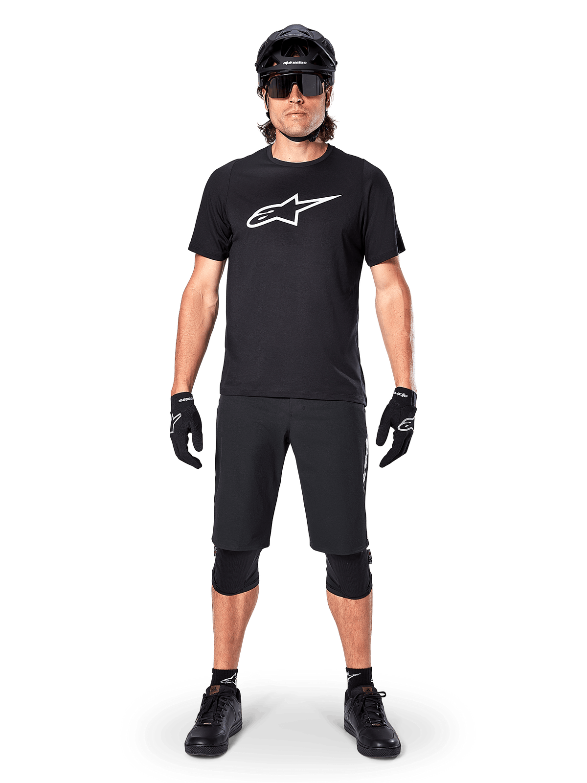 Alpinestars A-Dura Dri Oscar Short Sleeve Jersey, Black Reflective, worn with matching black MTB shorts, gloves, knee pads, and helmet, featuring a large white Alpinestars logo on the chest, complete mountain biking outfit