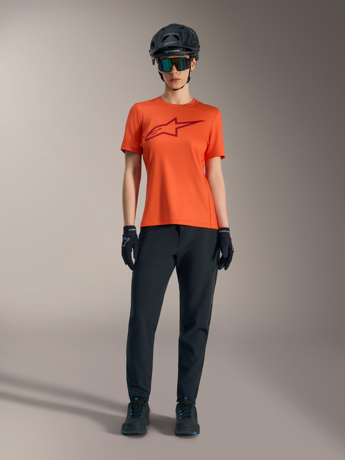 Orange Stella A-Dura Ride Short Sleeve Jersey with a maroon logo, worn with black MTB gear, helmet, and gloves.
