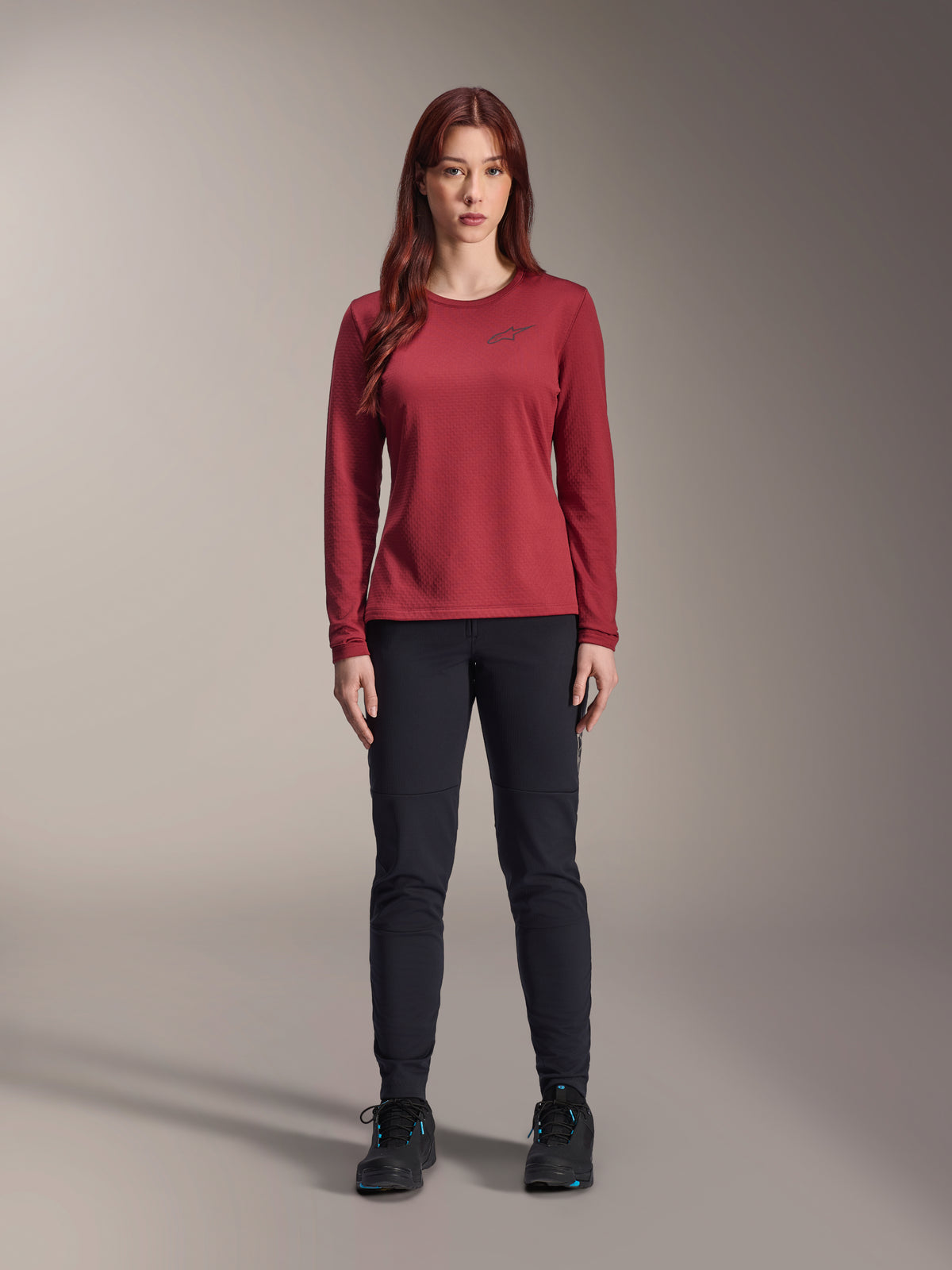 Alpinestars Stella A-Dura Thermal Jersey Feminina, camisola de ciclismo de manga comprida, cor de vinho, vestida por modelo feminina com calças pretas e sapatos pretos, apresenta logótipo discreto no peito, corte regular para ciclismo de montanha