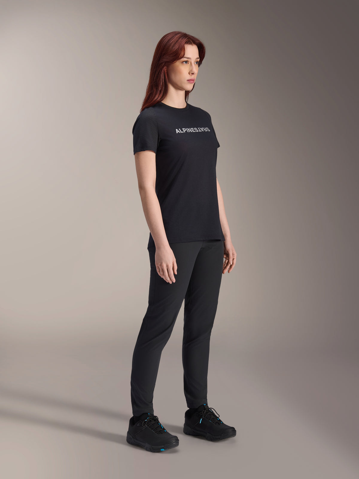 Alpinestars Stella A-Dura Dri Switch Jersey, camisola de ciclismo de manga curta, preta com logótipo Alpinestars branco, usada por modelo feminina com calças e sapatos pretos a condizer, equipamento versátil para mountain bike