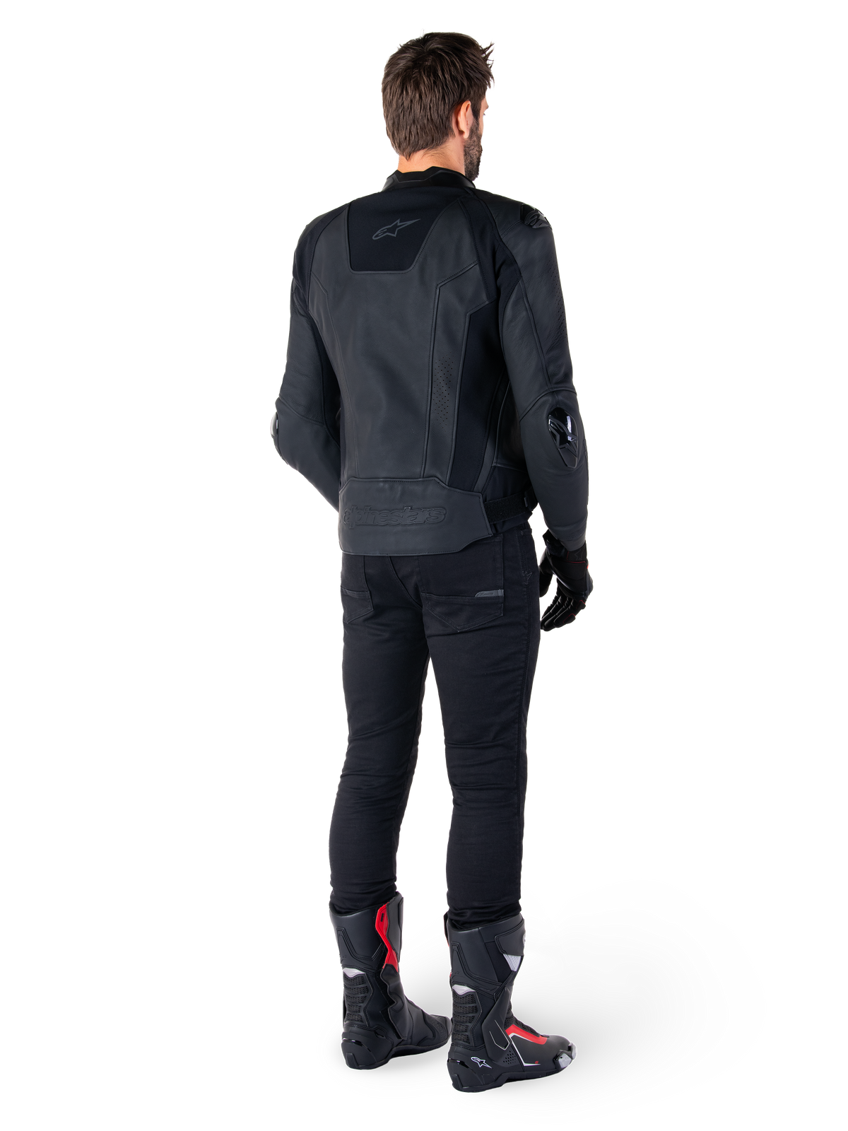 Casaco de Couro Alpinestars Missile V3 em preto, vista traseira num piloto, usado com calças pretas e botas de corrida pretas e vermelhas, com construção em couro elegante, logótipos tonais e ajuste de corrida de alta performance