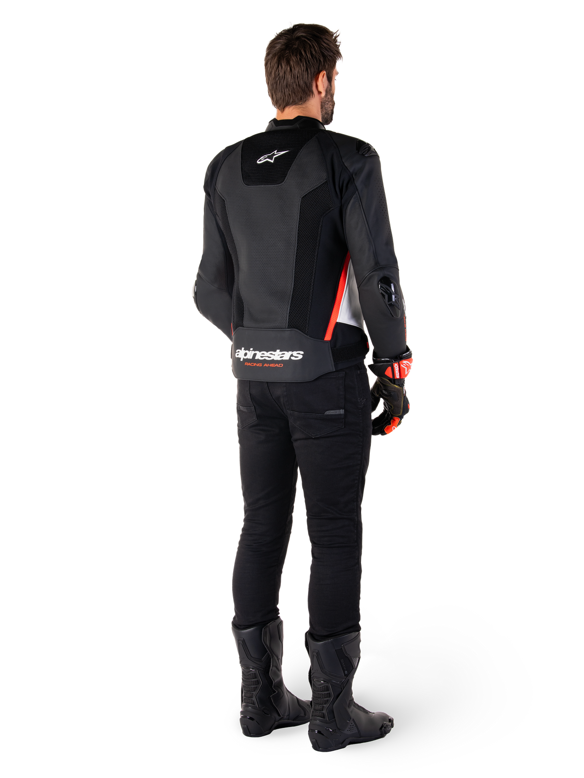 Piloto visto de costas a usar o casaco de couro Alpinestars Missile V3 Airflow em Preto Branco Vermelho Fluo, combinado com calças pretas e botas pretas, com couro perfurado extensivo para ventilação, proteções de ombro DFS e marca Alpinestars proeminente na parte inferior das costas.