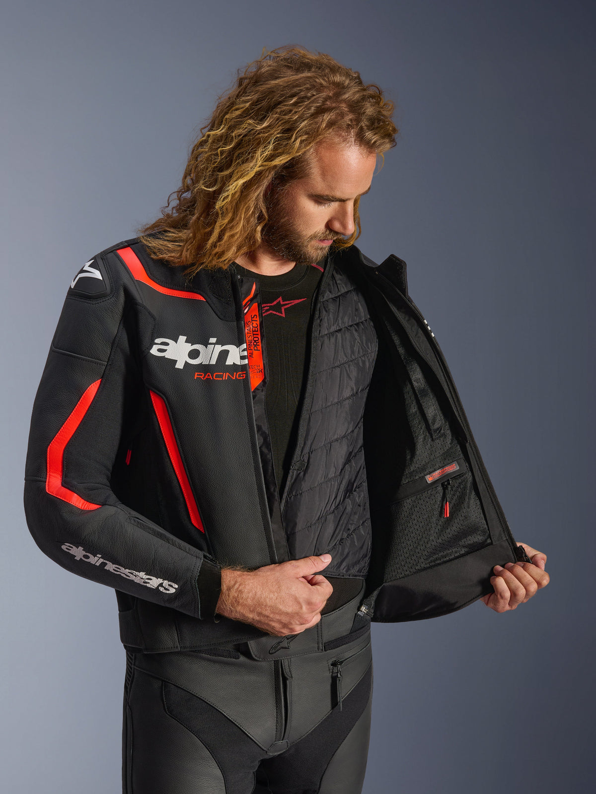 Alpinestars GP Force V2 Leather Jacket in Black and Red Fluo, detailed interior view on model showing the detachable thermal vest and waterproof inner pocket, premium leather construction for sport riding protection.