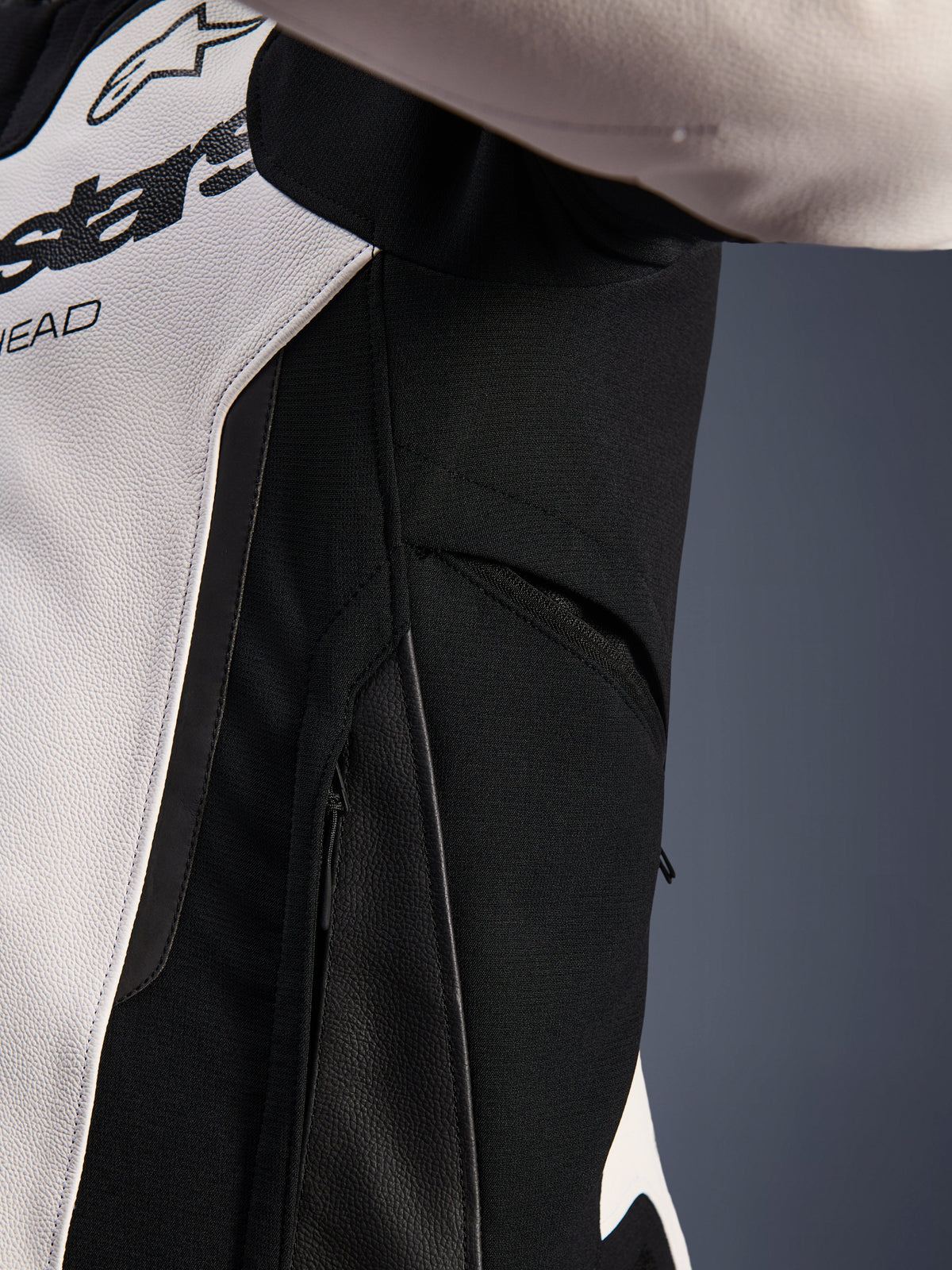 Close-up detail of the Alpinestars GP Force V2 Leather Jacket in White and Black, highlighting the zippered side ventilation and high-resistance stretch fabric panels for enhanced airflow and rider mobility.