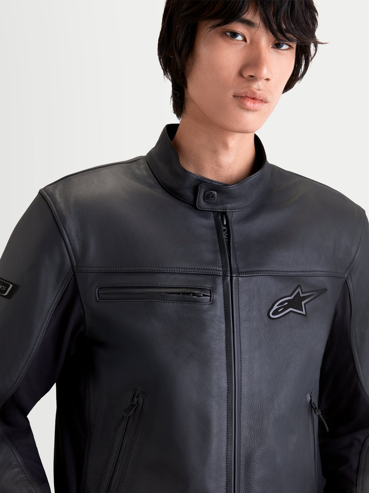 Alpinestars Maver X, blusão de moto contemporâneo para homem em preto, vista frontal em primeiro plano num modelo a usar equipamento em couro premium com bolsos com fecho e gola em estilo biker