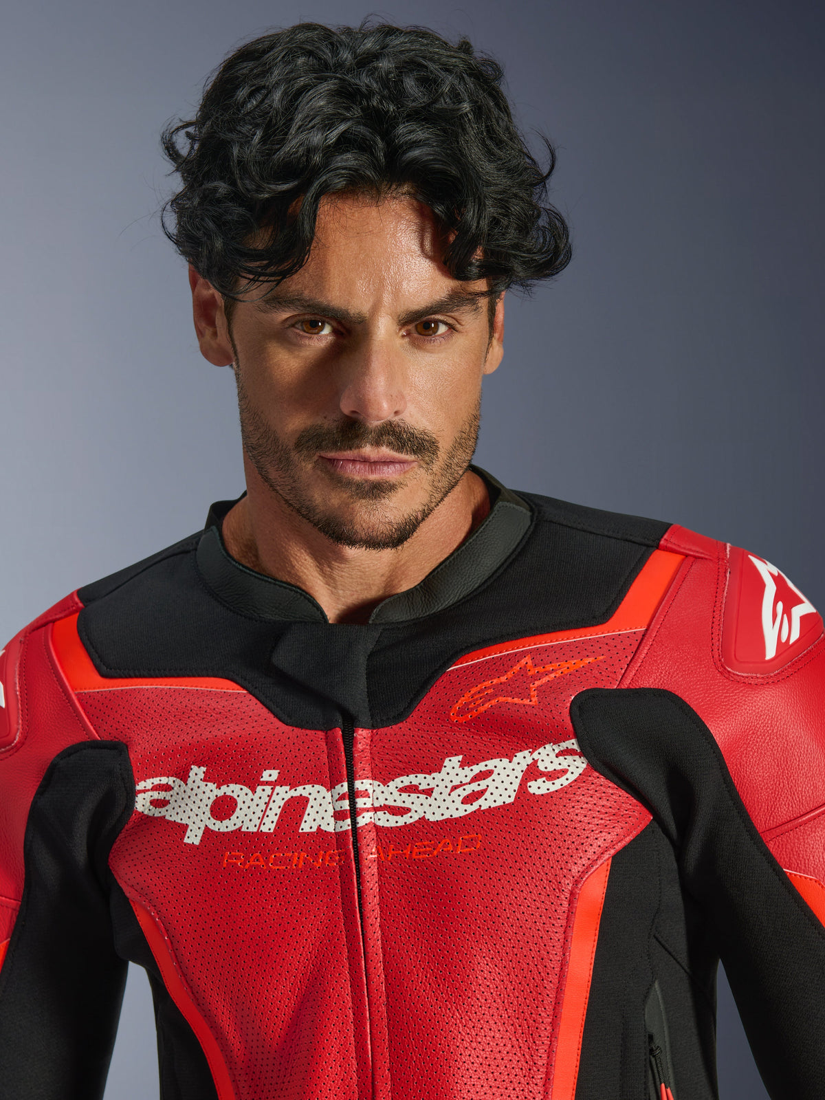 Alpinestars GP Force V2 Air Leather Jacket, Red and Red Fluo, worn by a male model, featuring white Alpinestars and 'Racing Ahead' branding on the chest, perforated leather for airflow, sport-style motorcycle gear